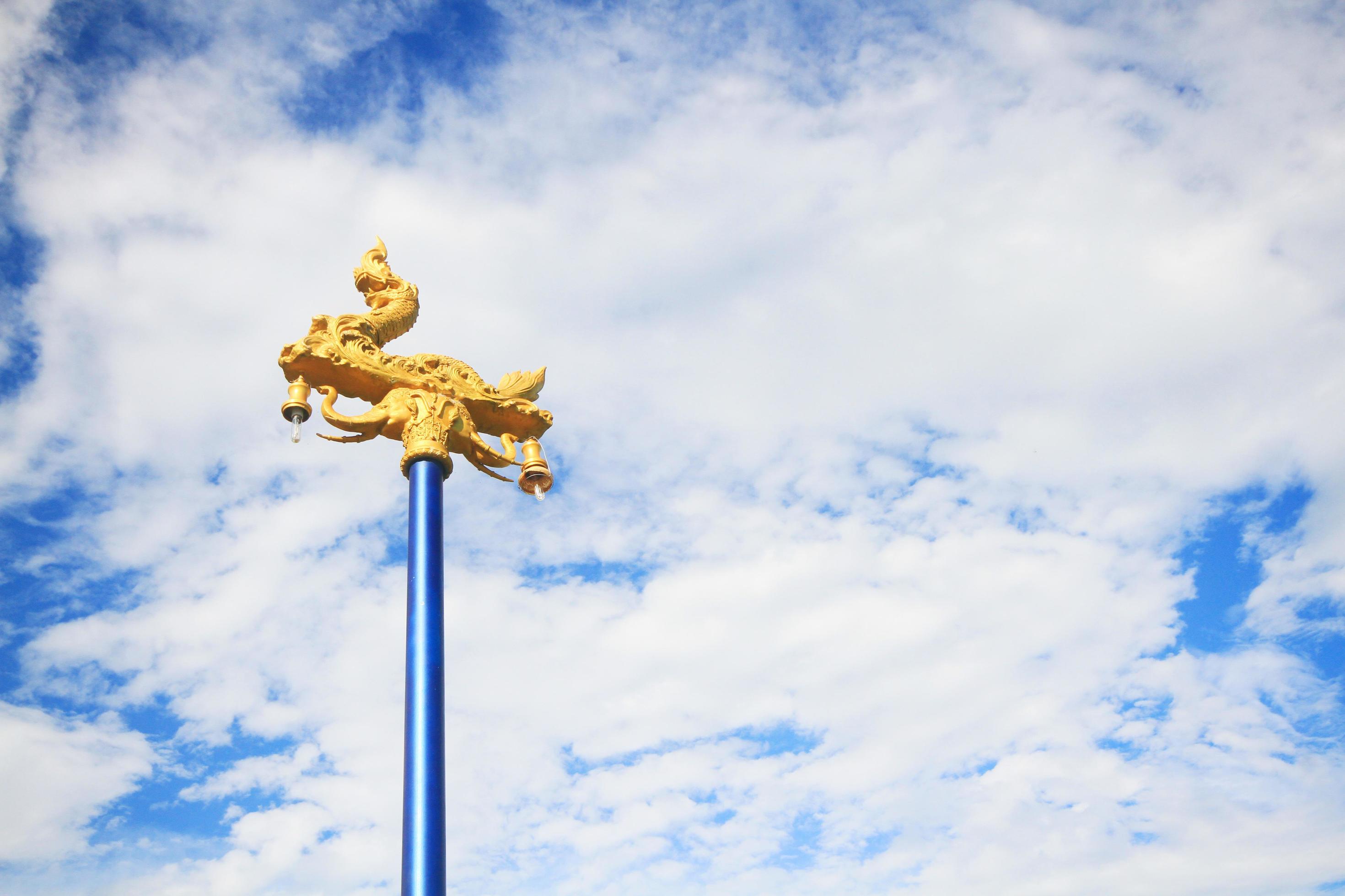 Beautiful golden Naga lamp on the street with blue sky in Thailand Stock Free