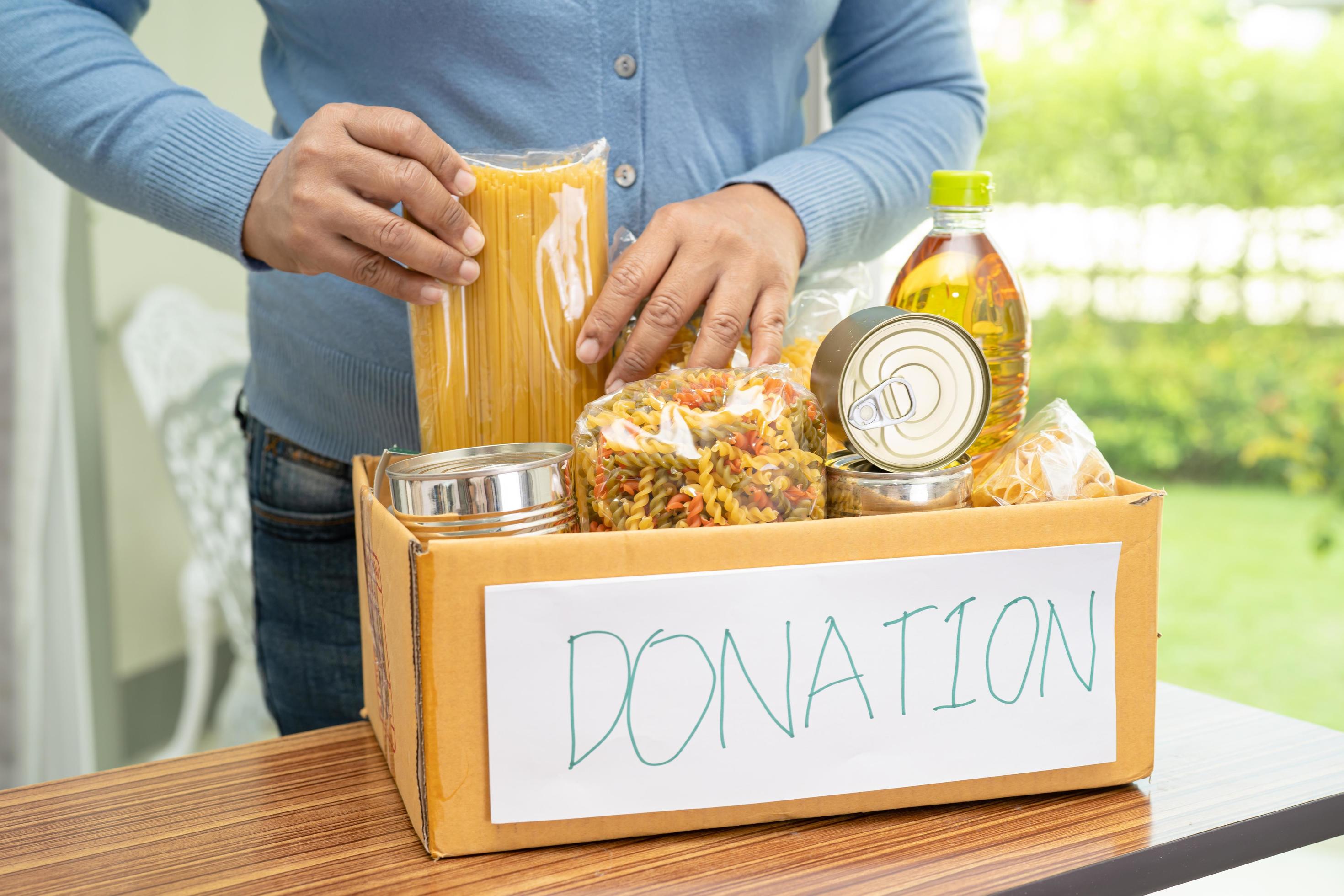 Volunteers putting various dry food in donation box for help people. Stock Free