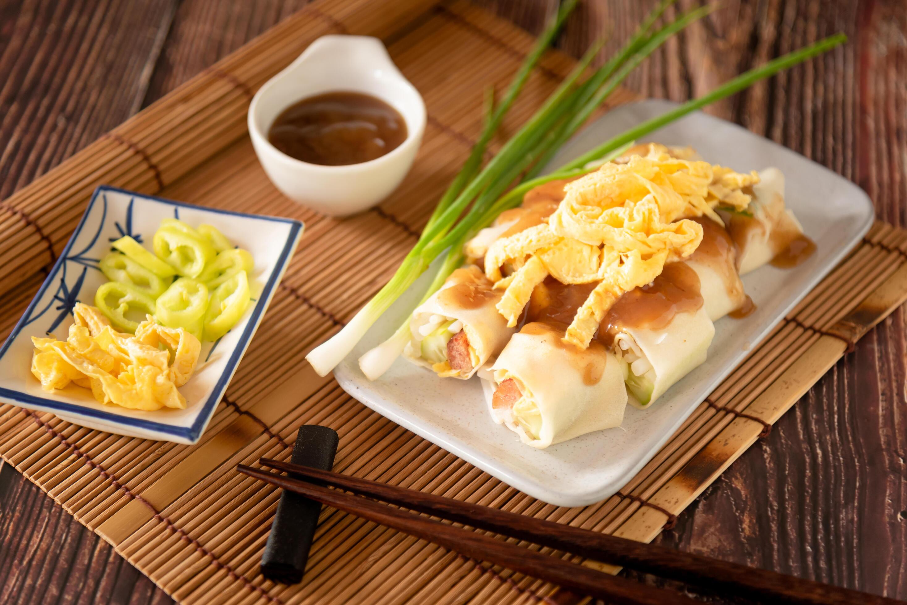 Thai traditional fresh spring roll with sweet sauce, stuff vegetable and sweet sausage on wooden background Stock Free