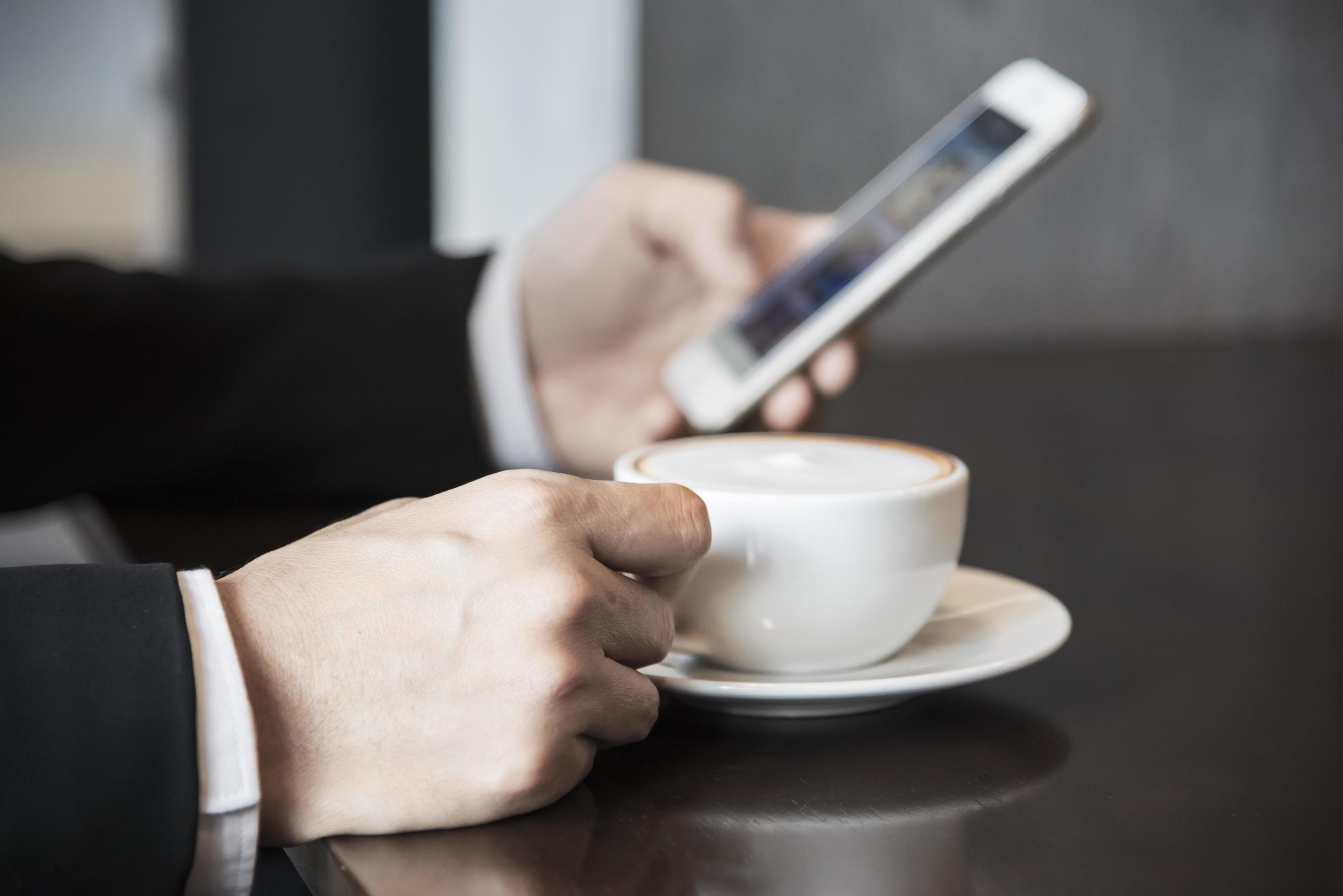 Business man using mobile phone while drinking coffee in coffee shop – modern life style business man in coffee shop concept Stock Free