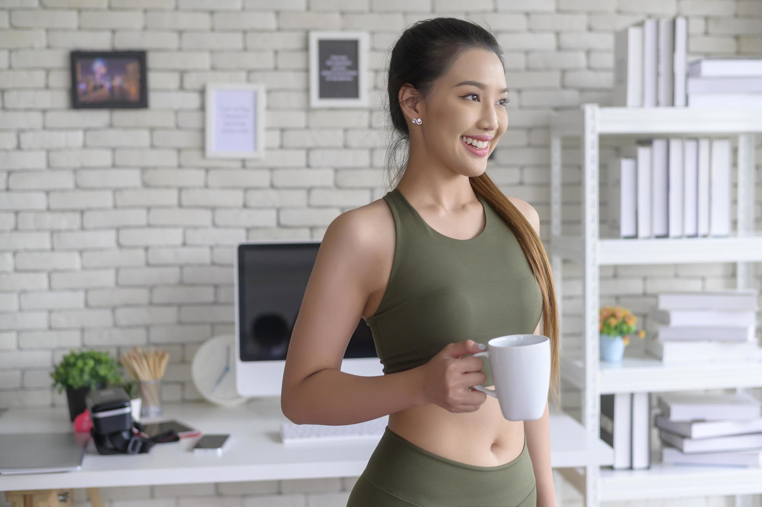 Young fitness woman in sportswear having a cup of coffee after exercising at home, Healthy and Lifestyles. Stock Free