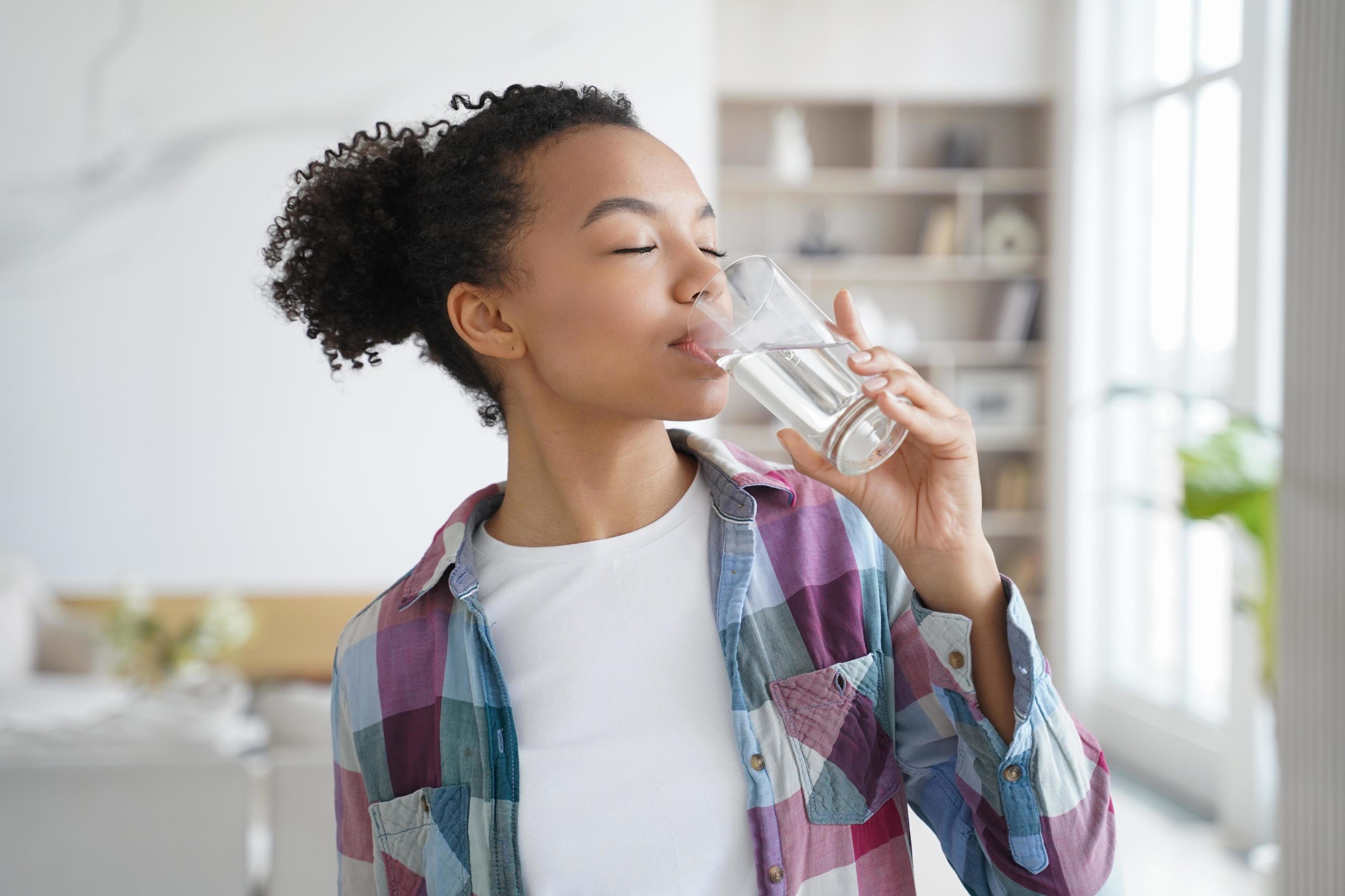 African american young girl enjoy drinking pure filtered water from glass at home. Healthy lifestyle Stock Free