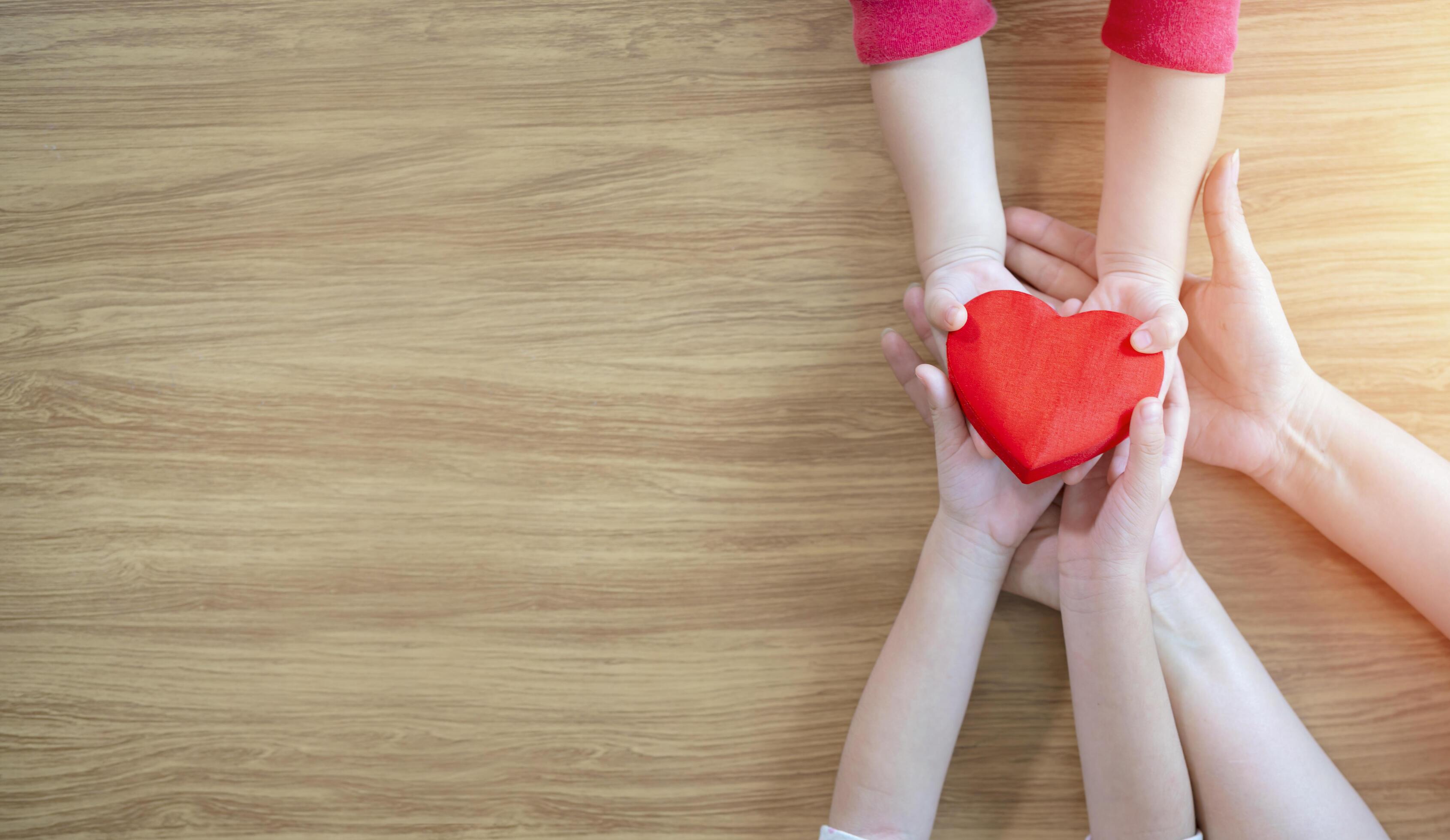 Adult and child hand holding red hearts on panorama Background., heart health, donation, CSR concept, world heart day, world health day, family day Stock Free