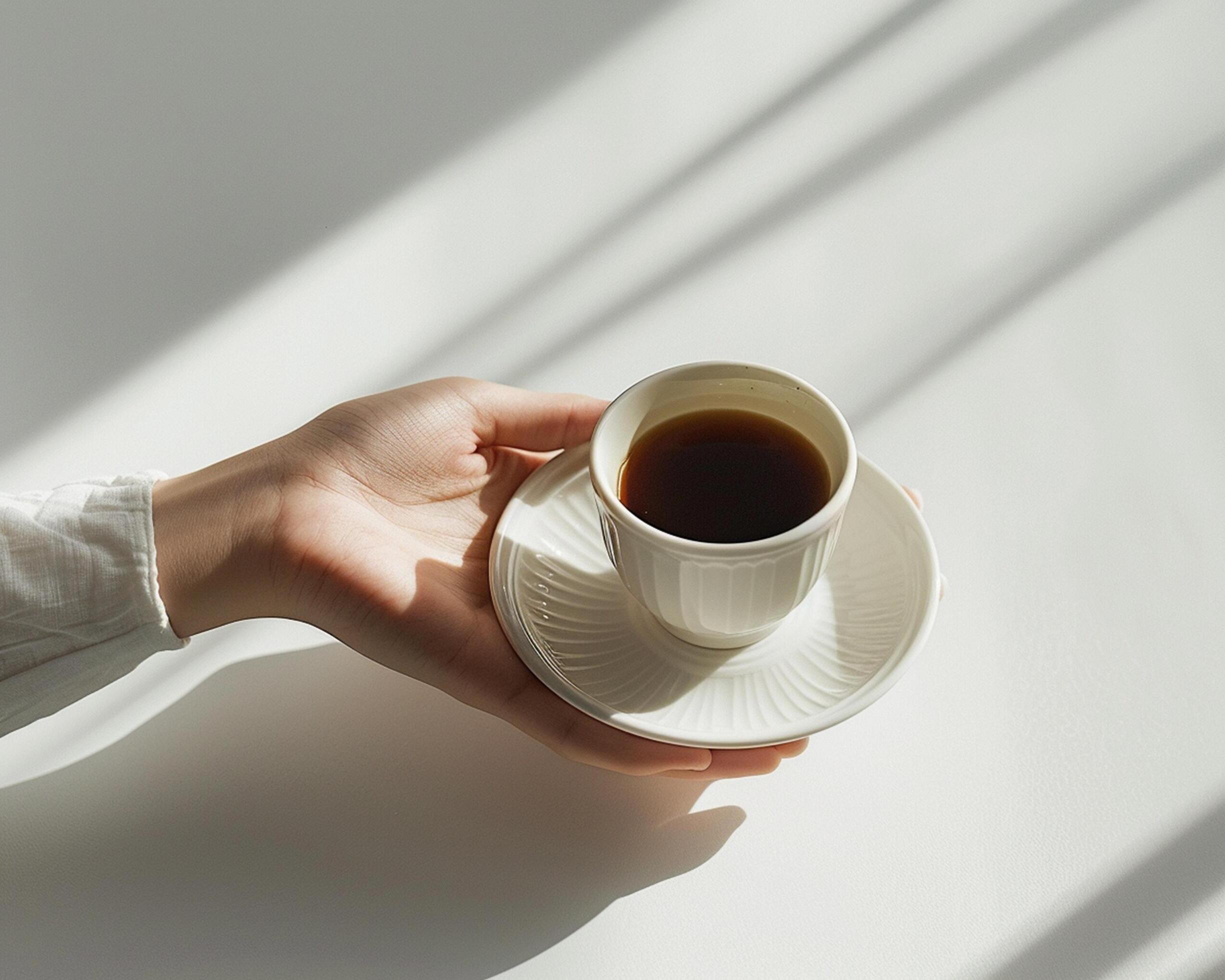 a person holding a cup of coffee on a white surface Stock Free