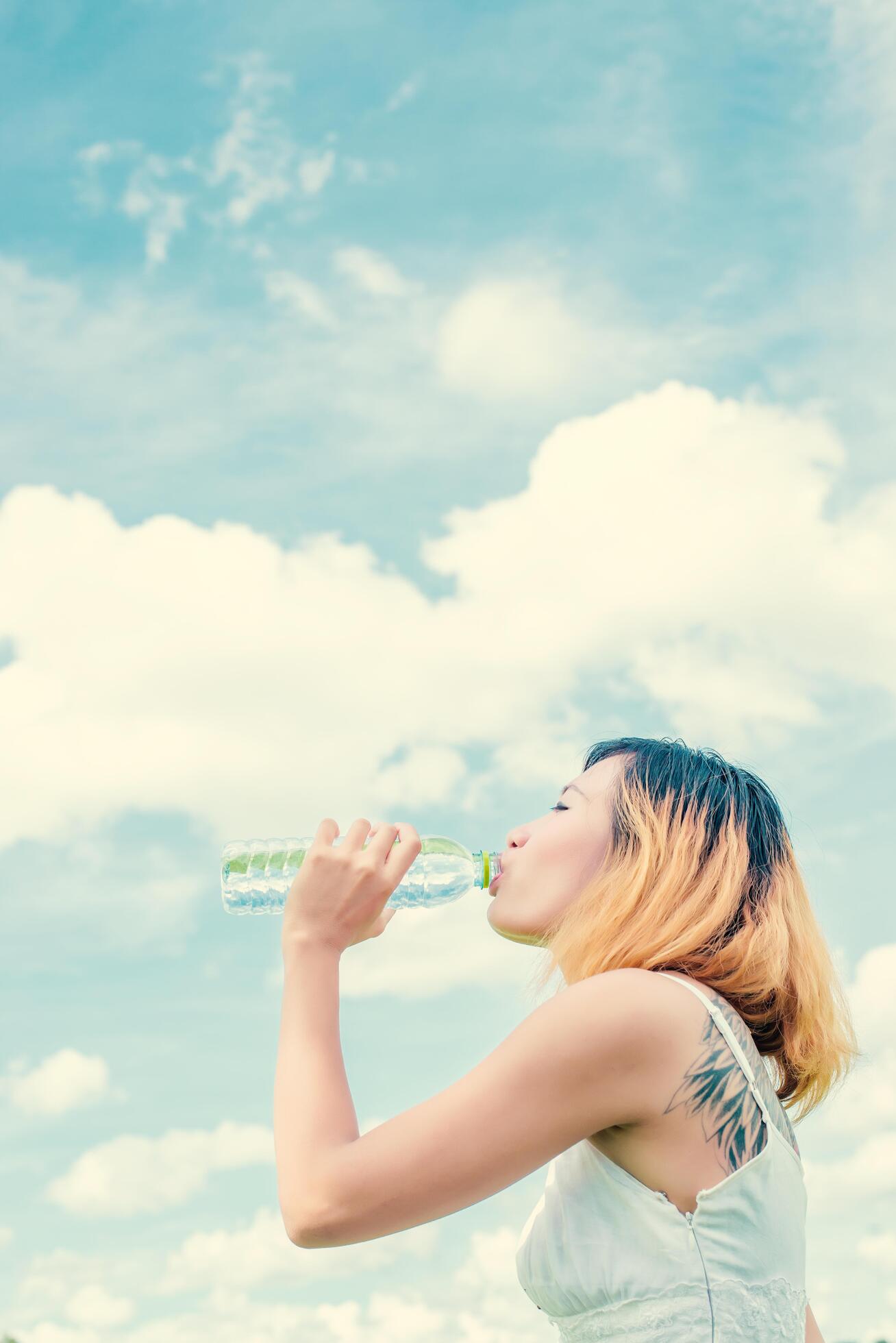 Women lifestyle concept young beautiful woman with white dress drinking water at summer green park. Stock Free