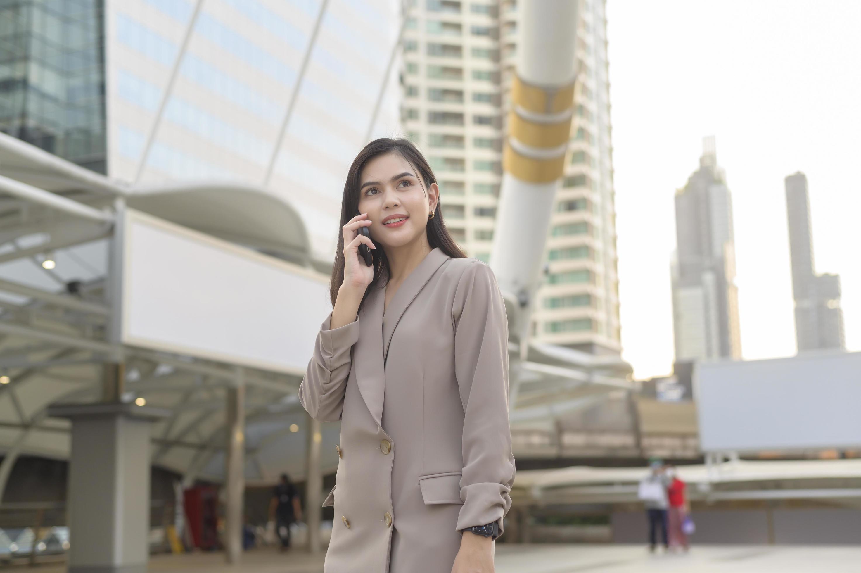 A young beautiful businesswoman is using Smart phone in Modern city , business technology , city lifestyle concept Stock Free