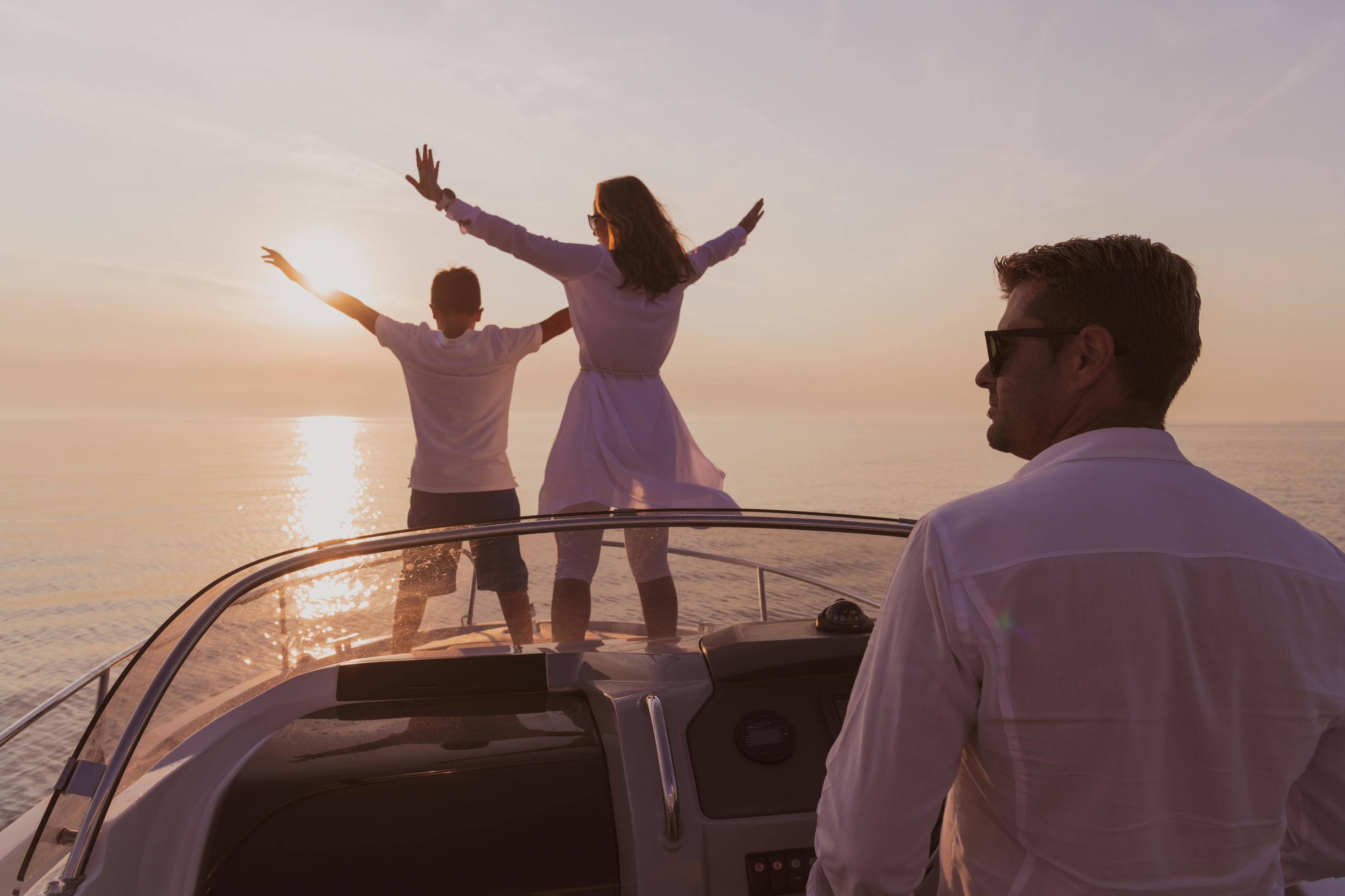 A senior couple in casual outfits with their son enjoy while riding a boat at sea at sunset. The concept of a happy family. Selective focus Stock Free