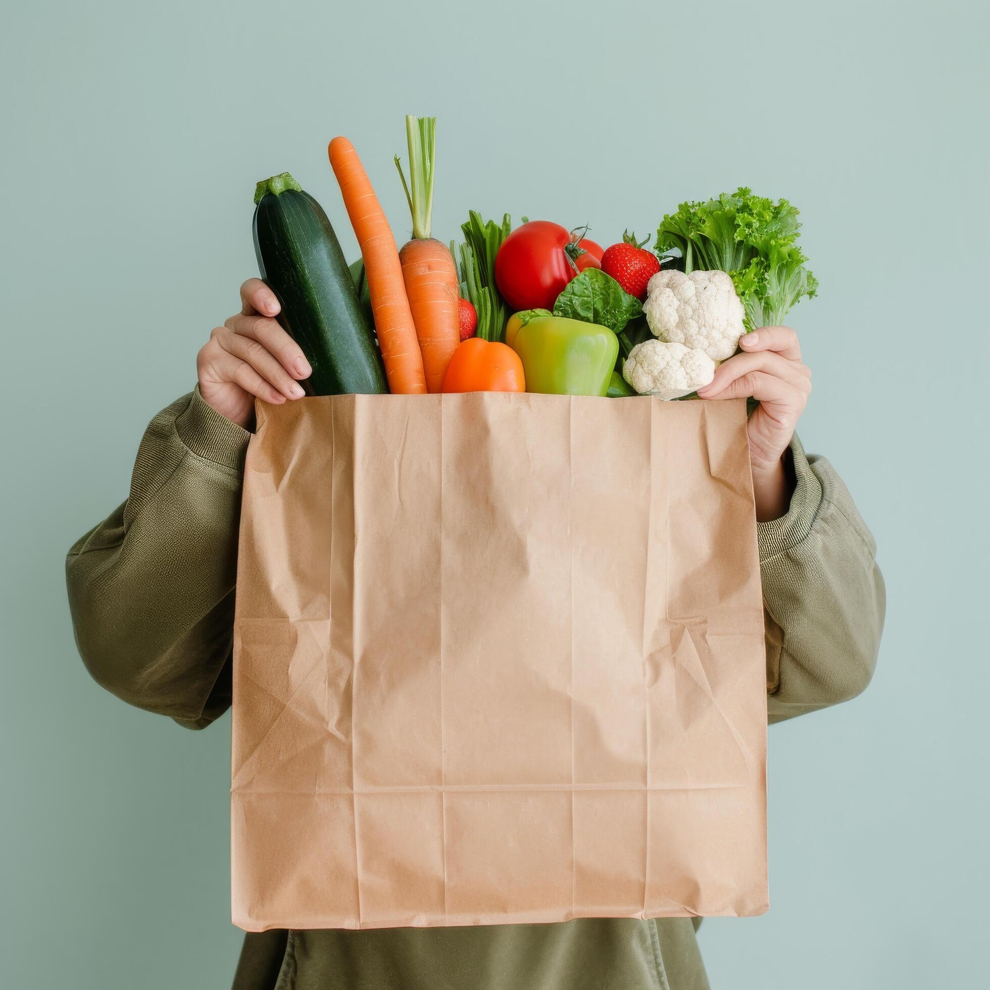 Fresh Vegetables and Greens in Brown Paper Bag Held by Person Against Light Background Stock Free