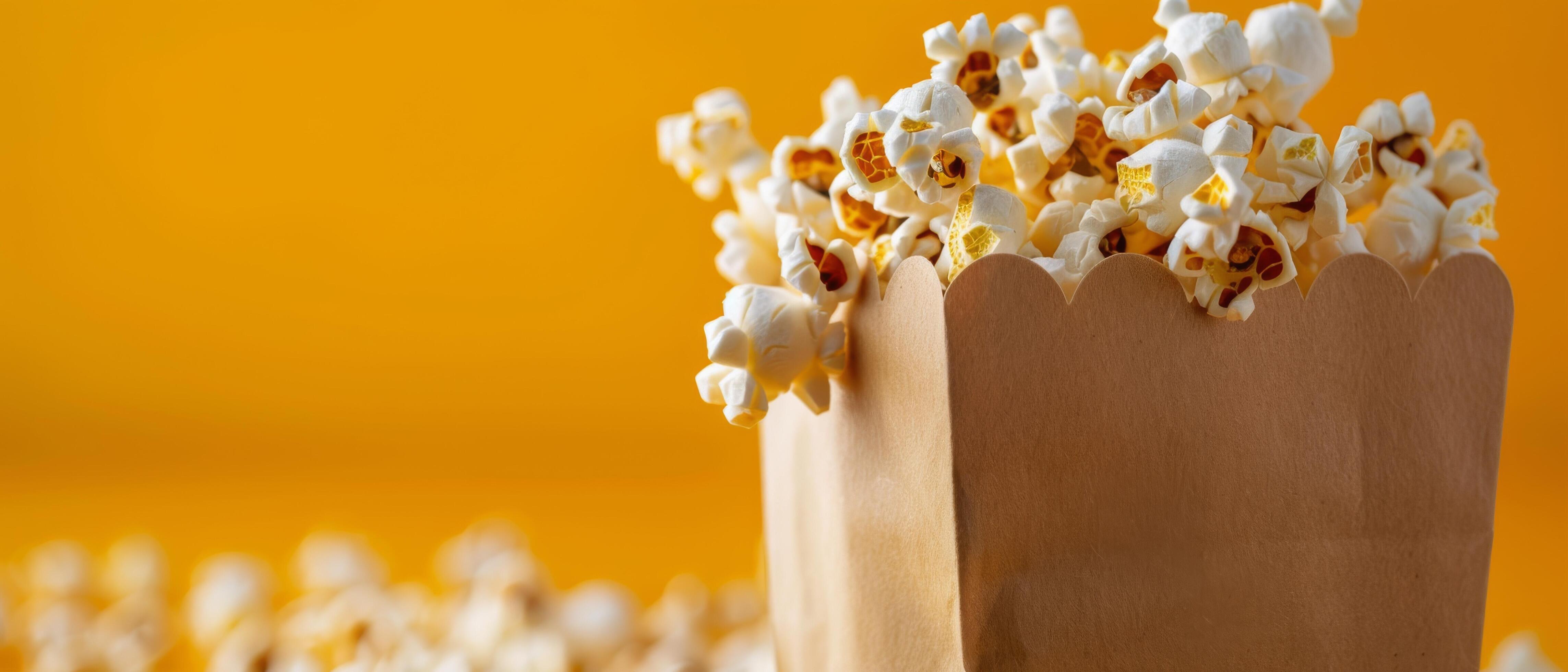 Freshly Popped Popcorn in a Striped Box Against a Bright Yellow Background Stock Free