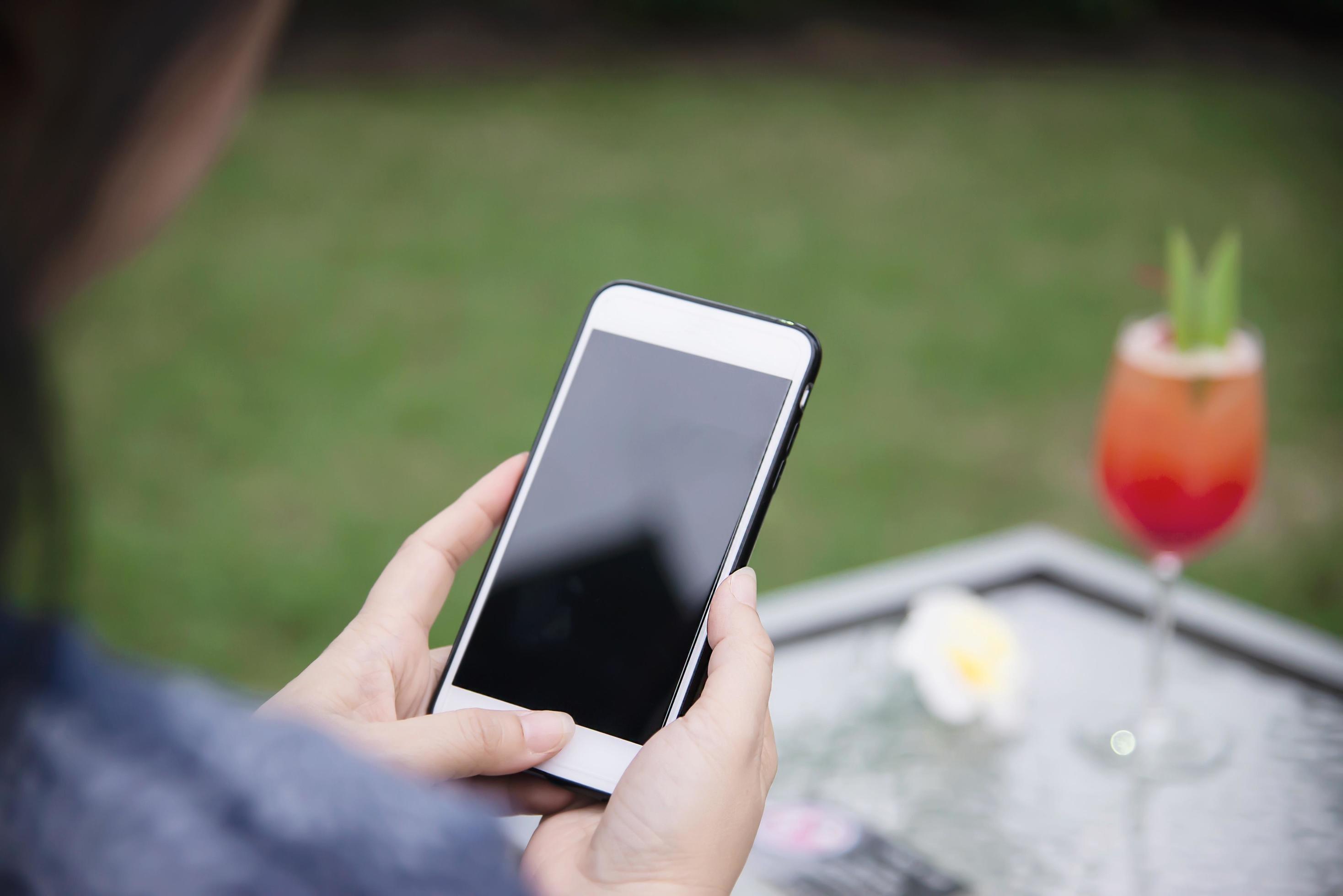 Lady using mobile phone relax in green garden with soft drink background – people and technology lifestyle concept Stock Free