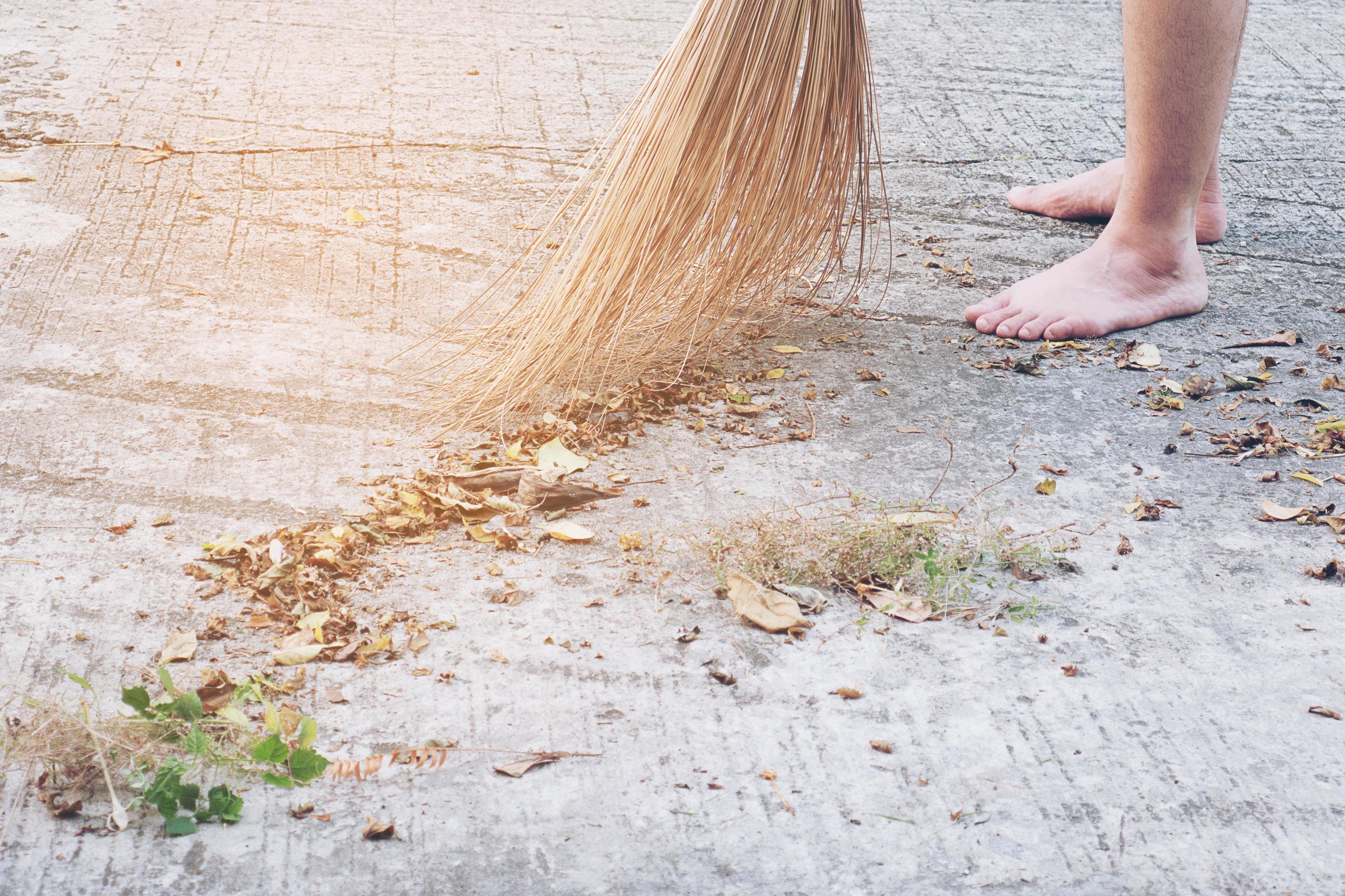 Man cleaning outdoor road using bloom made from dry coconut leave product – local people lifestyle concept in Thailand Stock Free