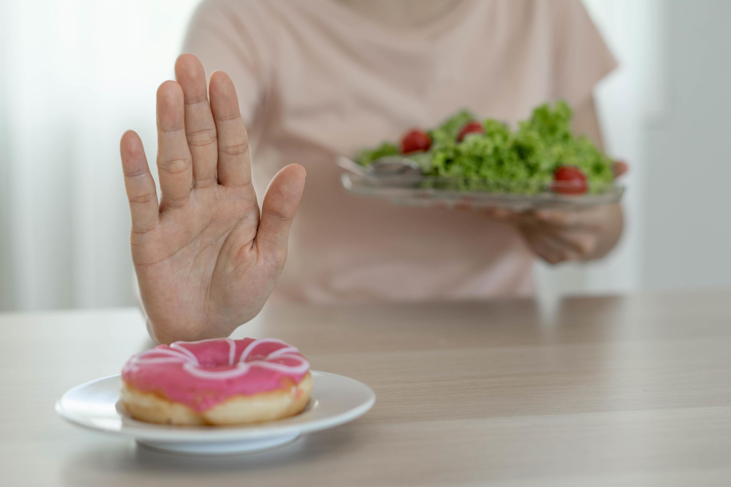 Good health food and diet. Women reject junk food or unhealthy foods such as doughnuts and choose healthy foods such as green apple. Stock Free