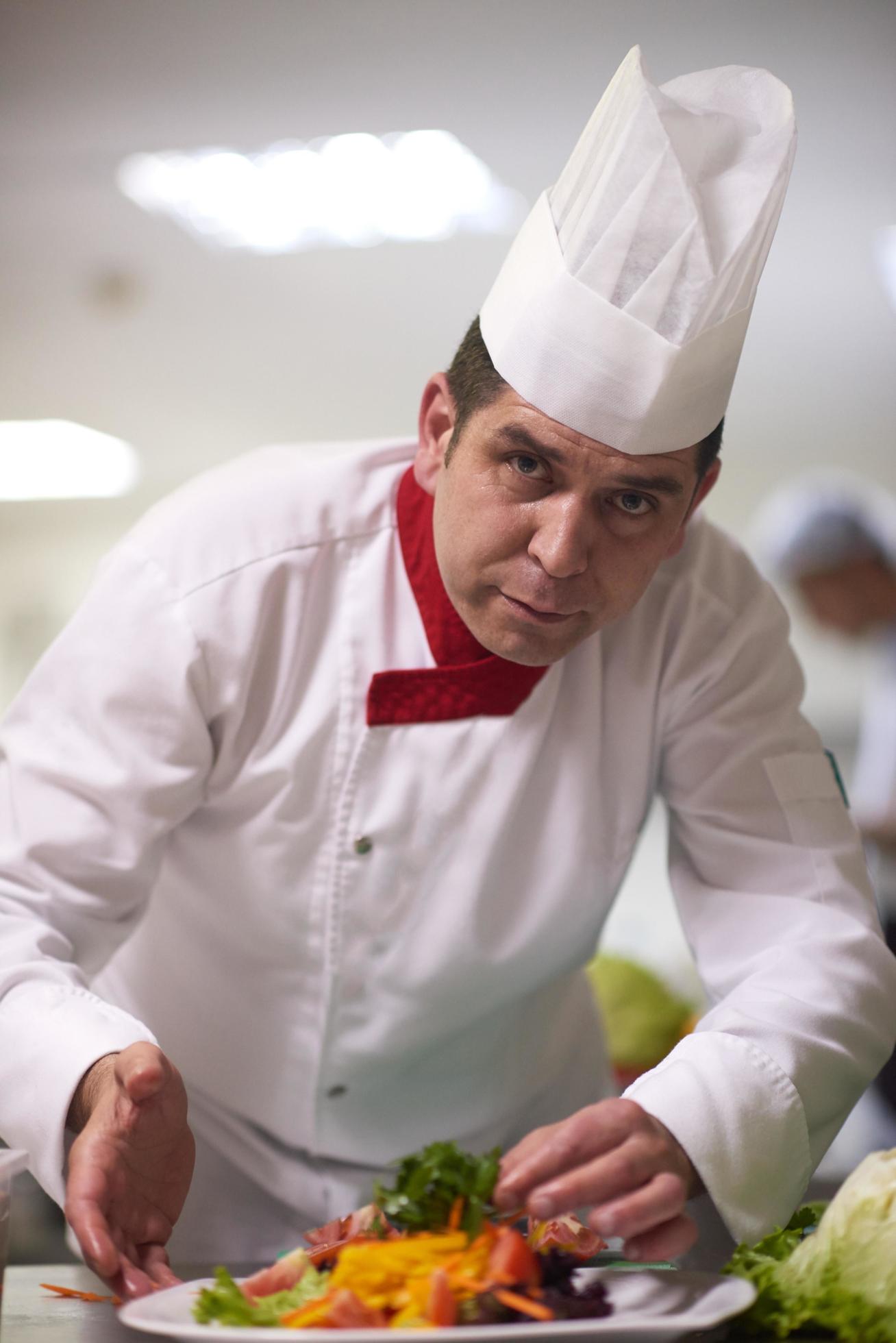 chef in hotel kitchen preparing and decorating food Stock Free