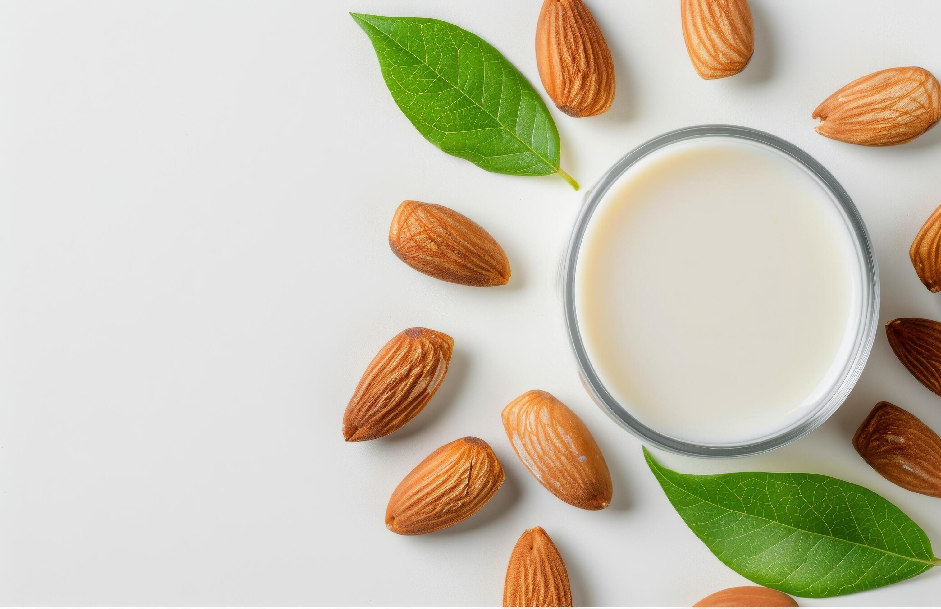 Creamy Almond Milk Surrounded by Almonds and Fresh Leaves on a White Background Stock Free