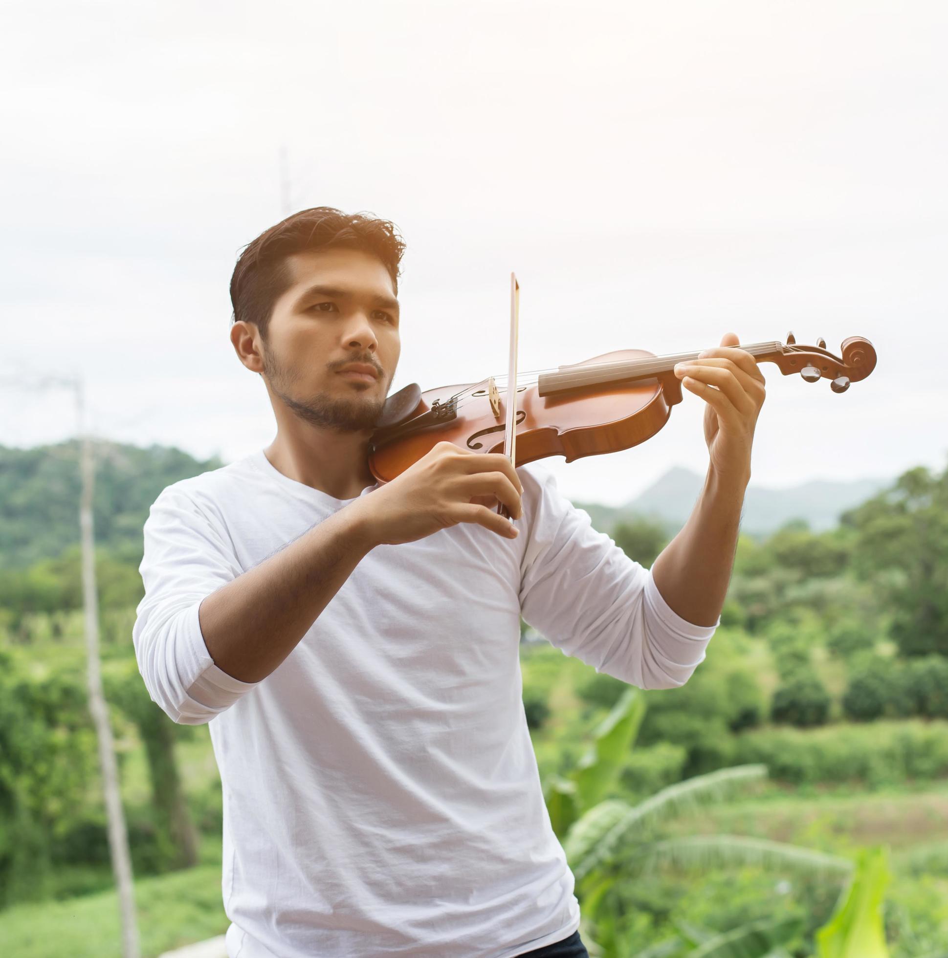 Young hipster musician man playing violin in the nature outdoor lifestyle behind mountain. Stock Free