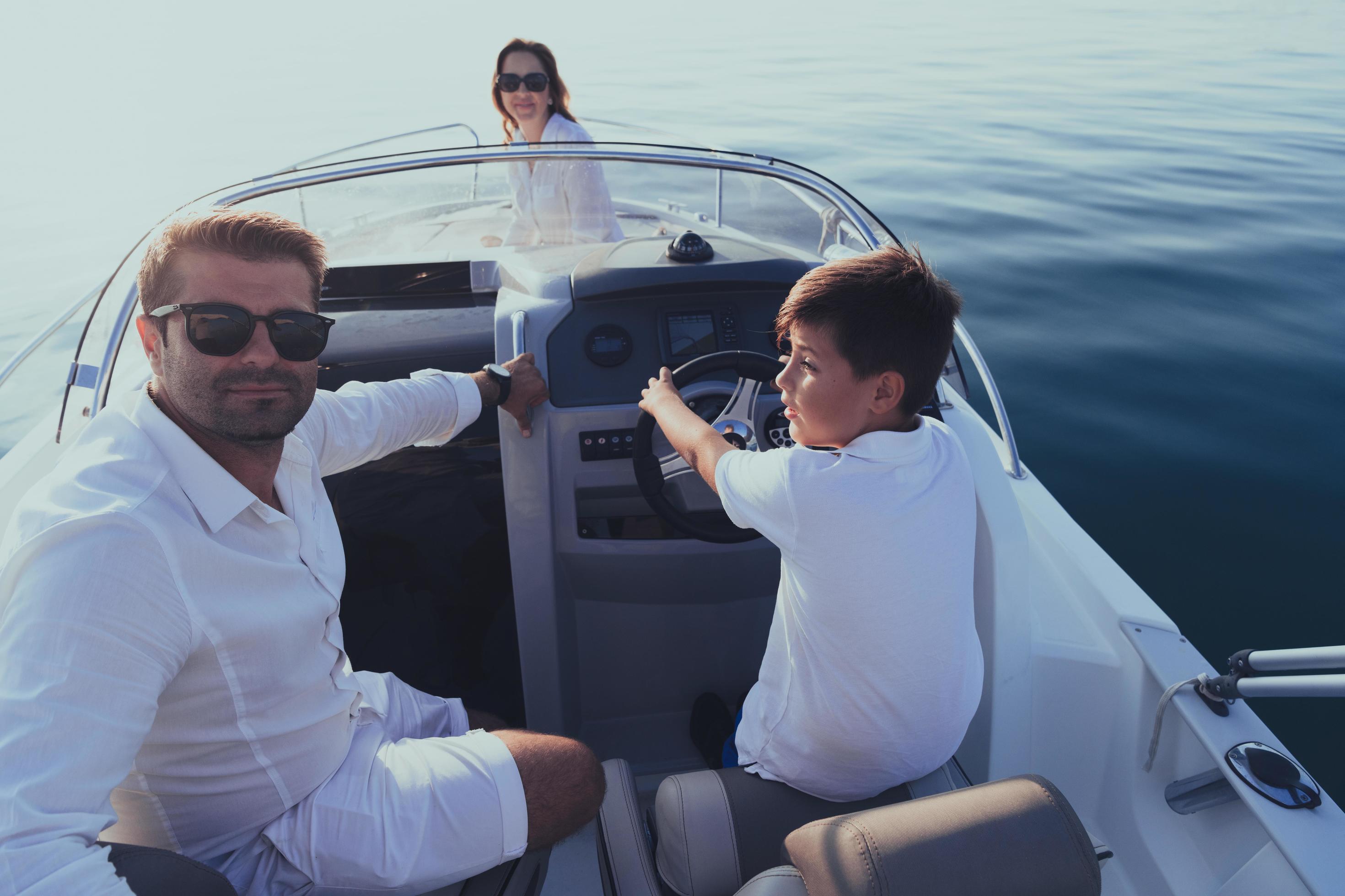 A senior couple in casual outfits with their son enjoy while riding a boat at sea at sunset. The concept of a happy family. Selective focus Stock Free