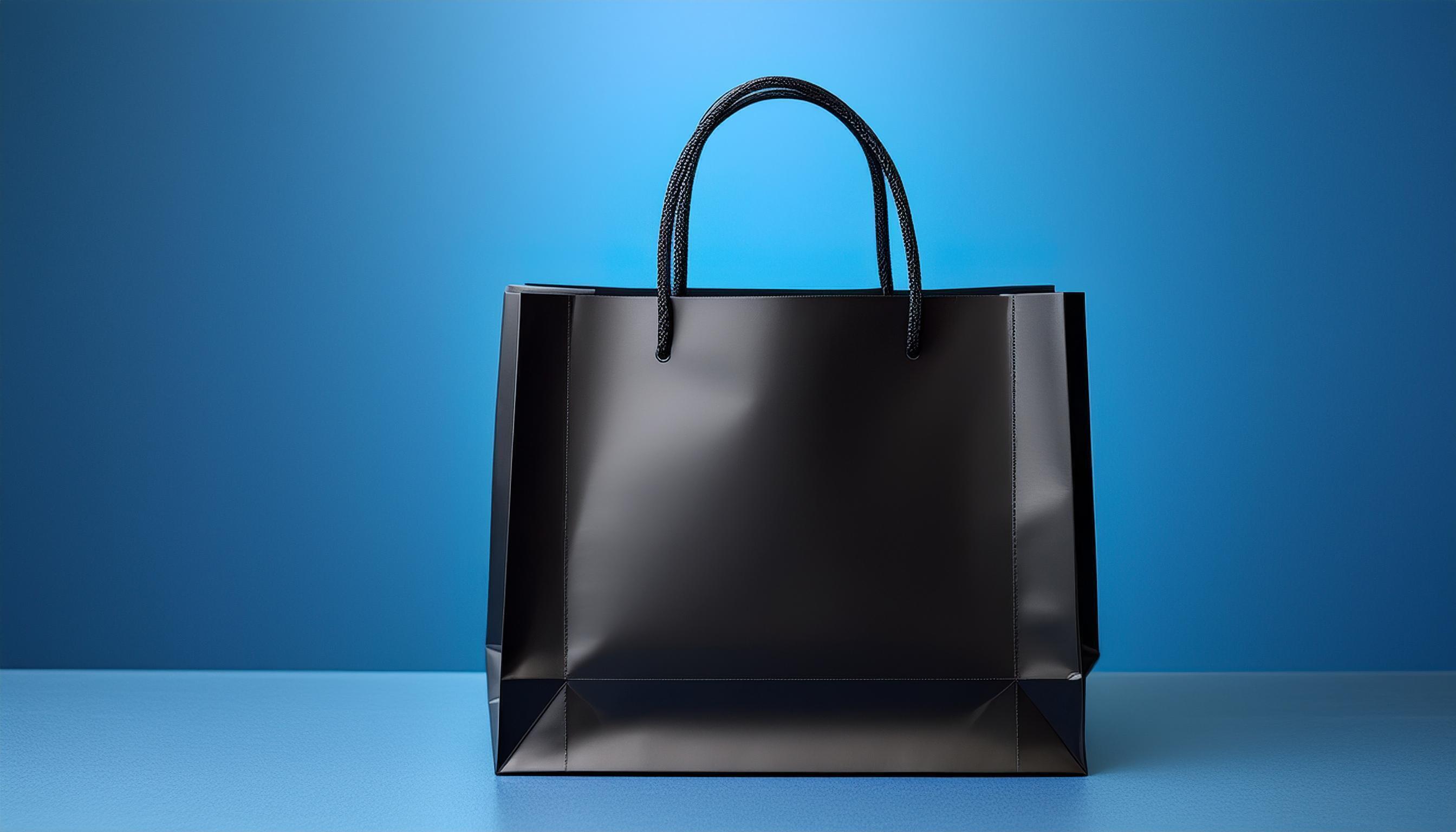 black shopping bag with empty space, blue studio background. Stock Free