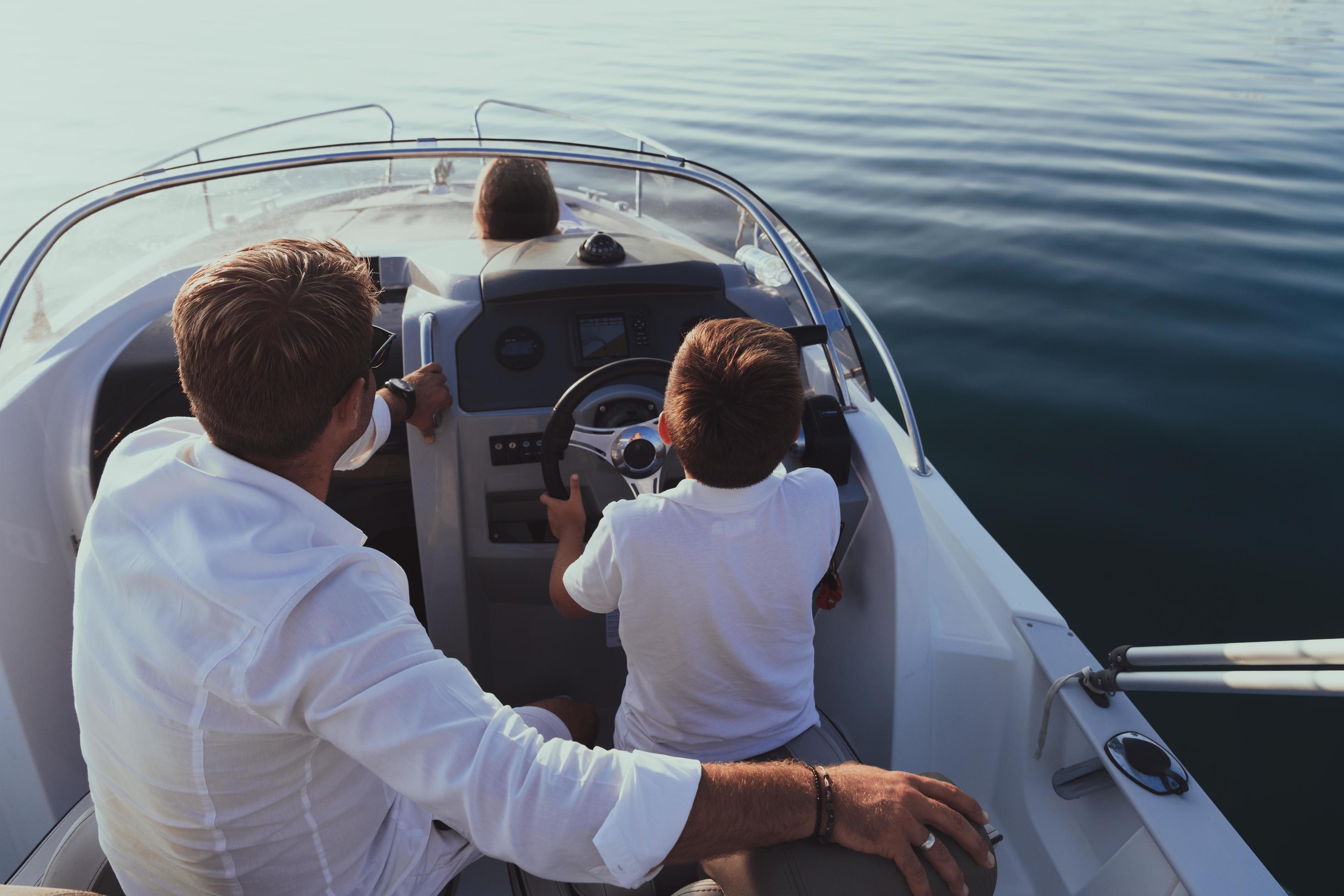 A senior couple in casual outfits with their son enjoy while riding a boat at sea at sunset. The concept of a happy family. Selective focus Stock Free