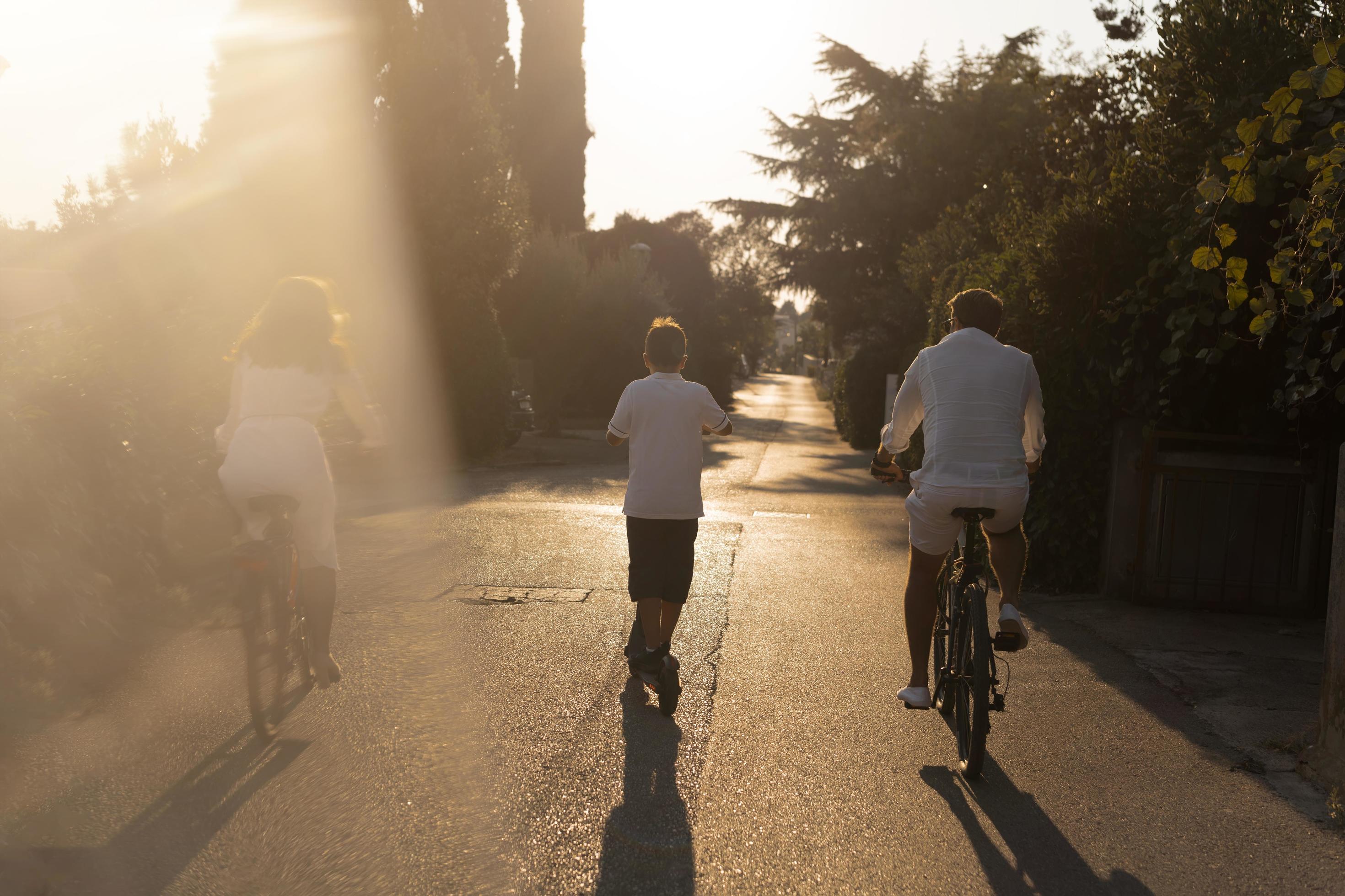 Happy family enjoying a beautiful morning together, parents riding a bike and their son riding an electric scooter. Selective focus Stock Free