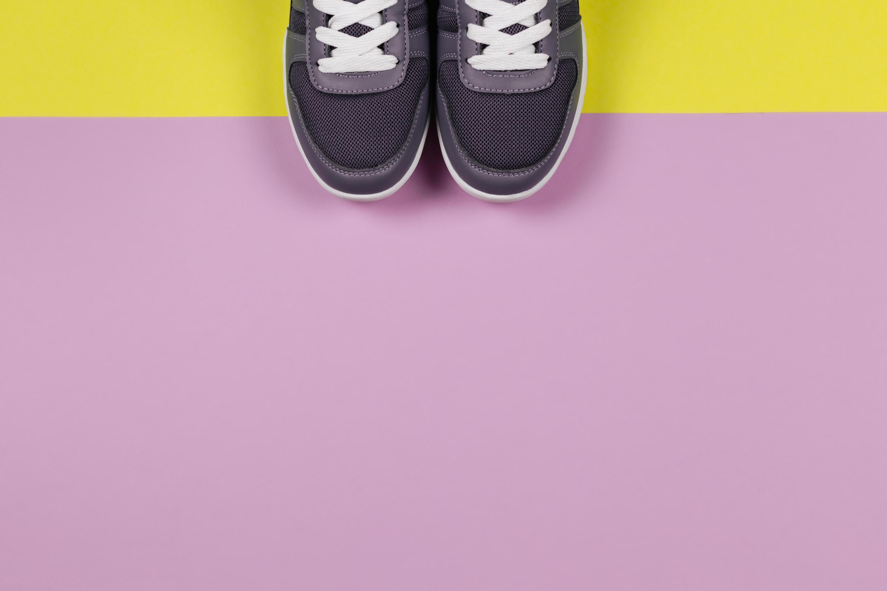 Grey sneakers on the yellow and violet background. Concept for healthy lifestyle and everyday training. Stock Free