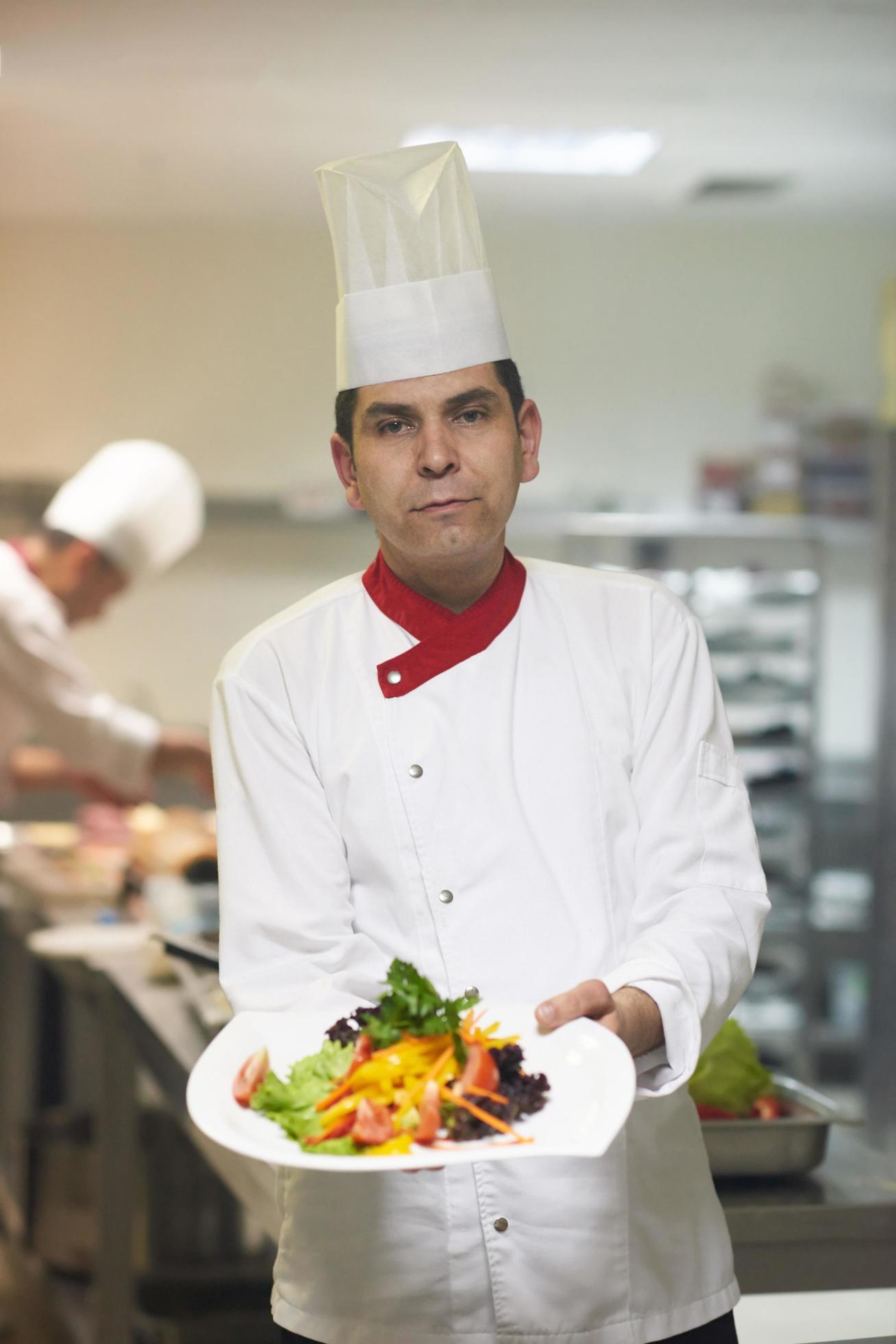 chef in hotel kitchen preparing and decorating food Stock Free