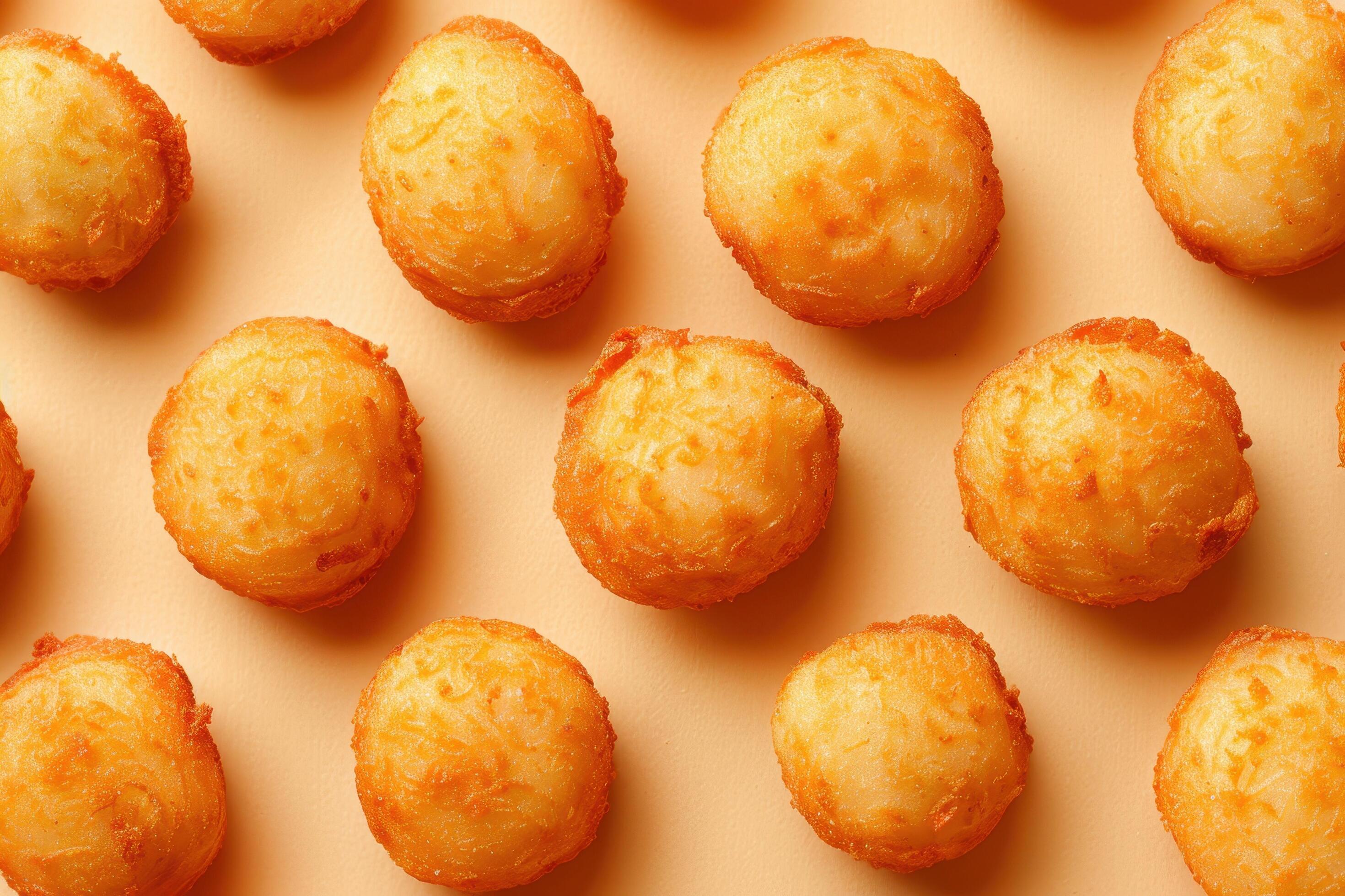 Golden Brown Fried Potato Balls on Orange Background Stock Free