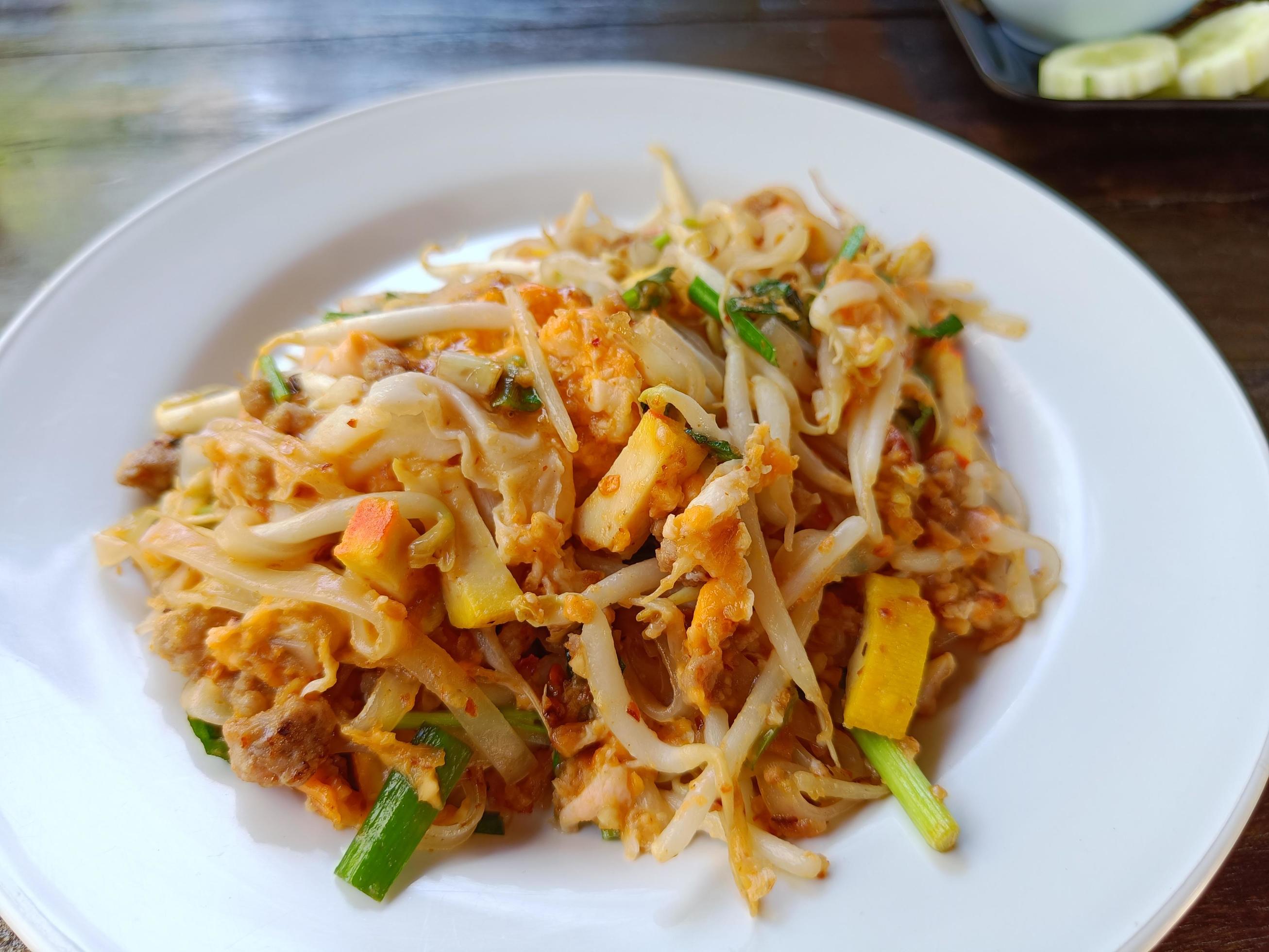 Pad Thai with minced pork and tofu on a white plate on the brown table popular Thai food Stock Free