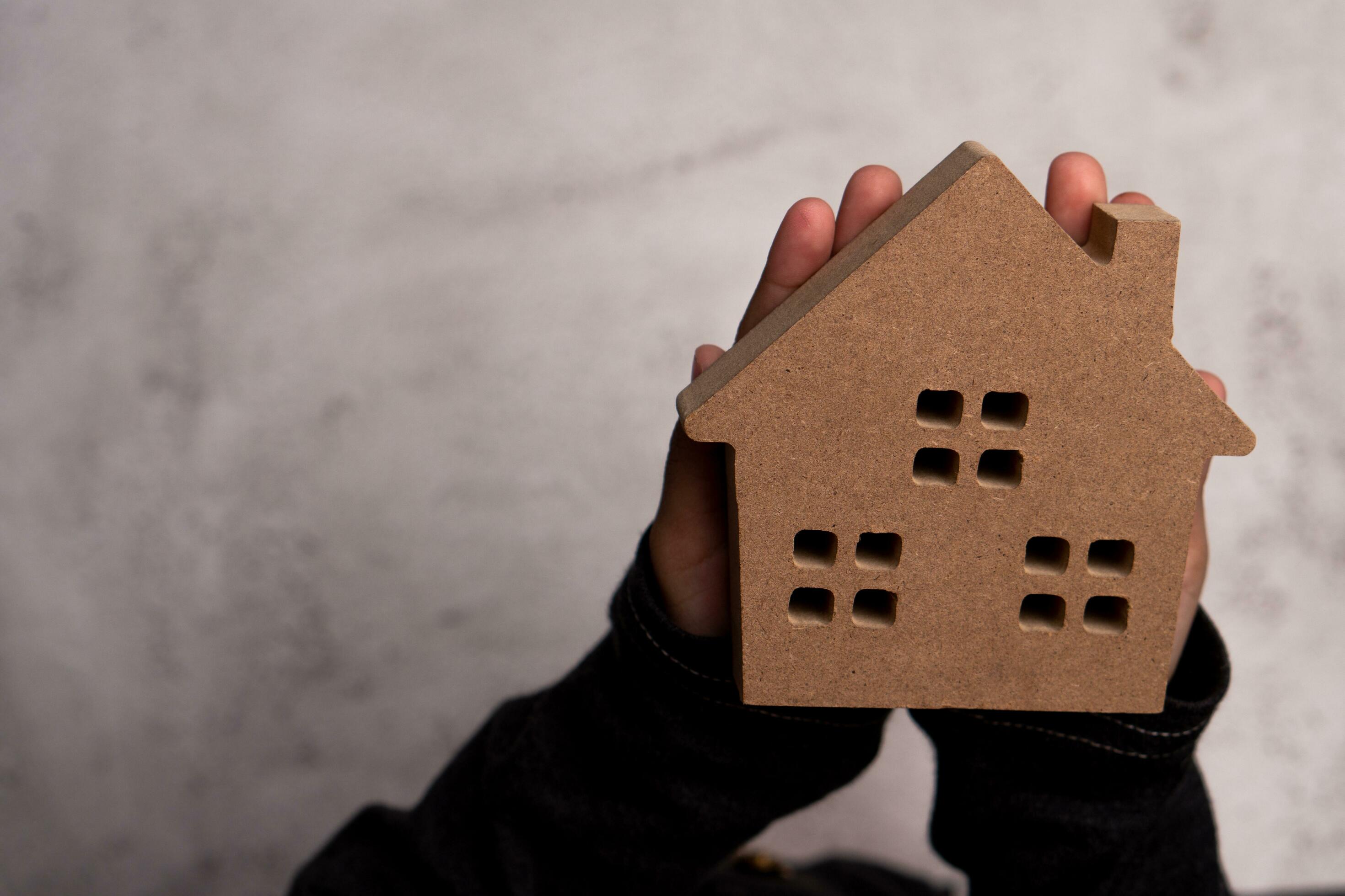 Child hand man holding a wooden model house. Concept of love family and security protection, Trust for construction and home renovation. Stock Free