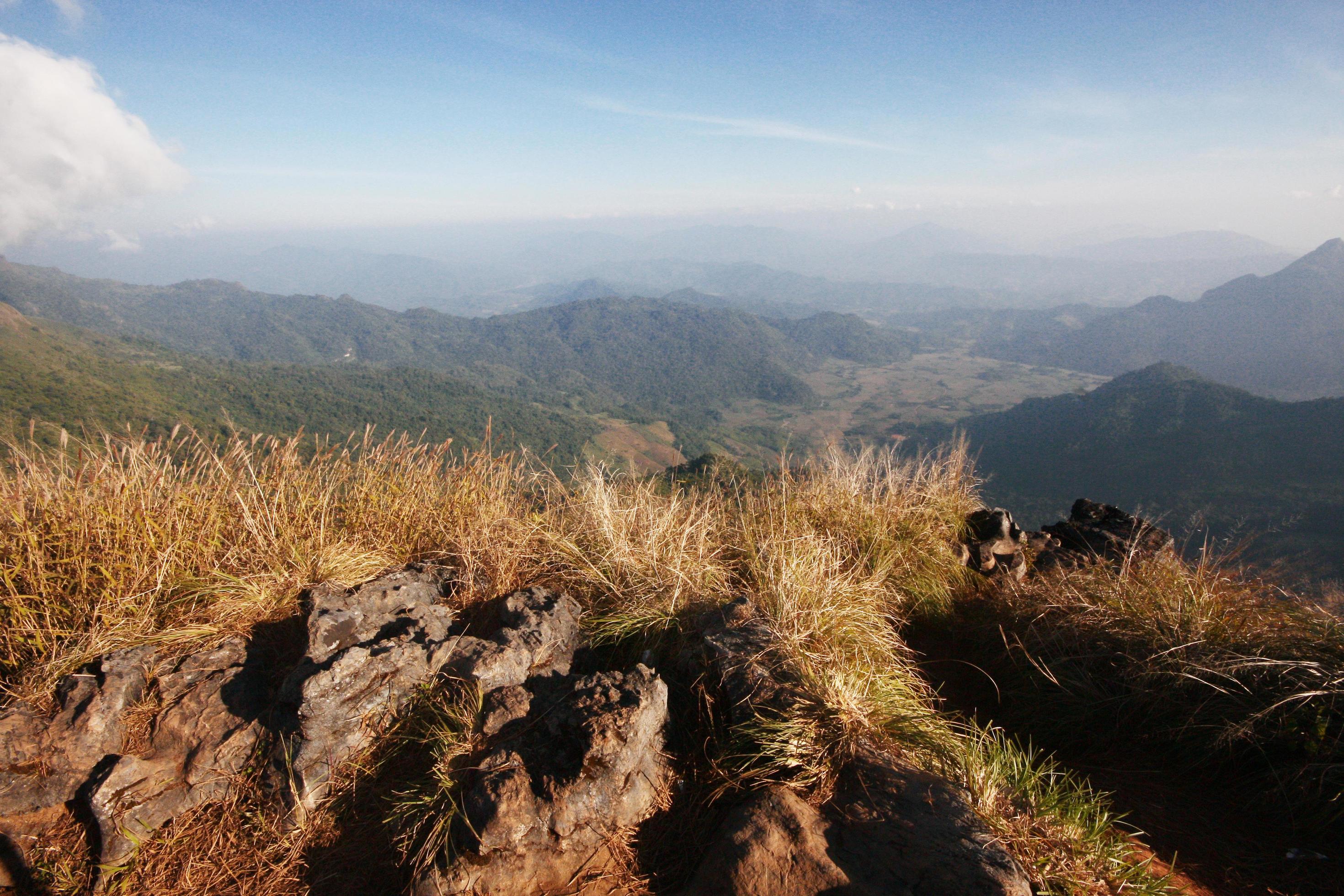 Aerial view of hightland with dry grass and forest on rock hill in blue sky on the valley mountain in Thailand Stock Free