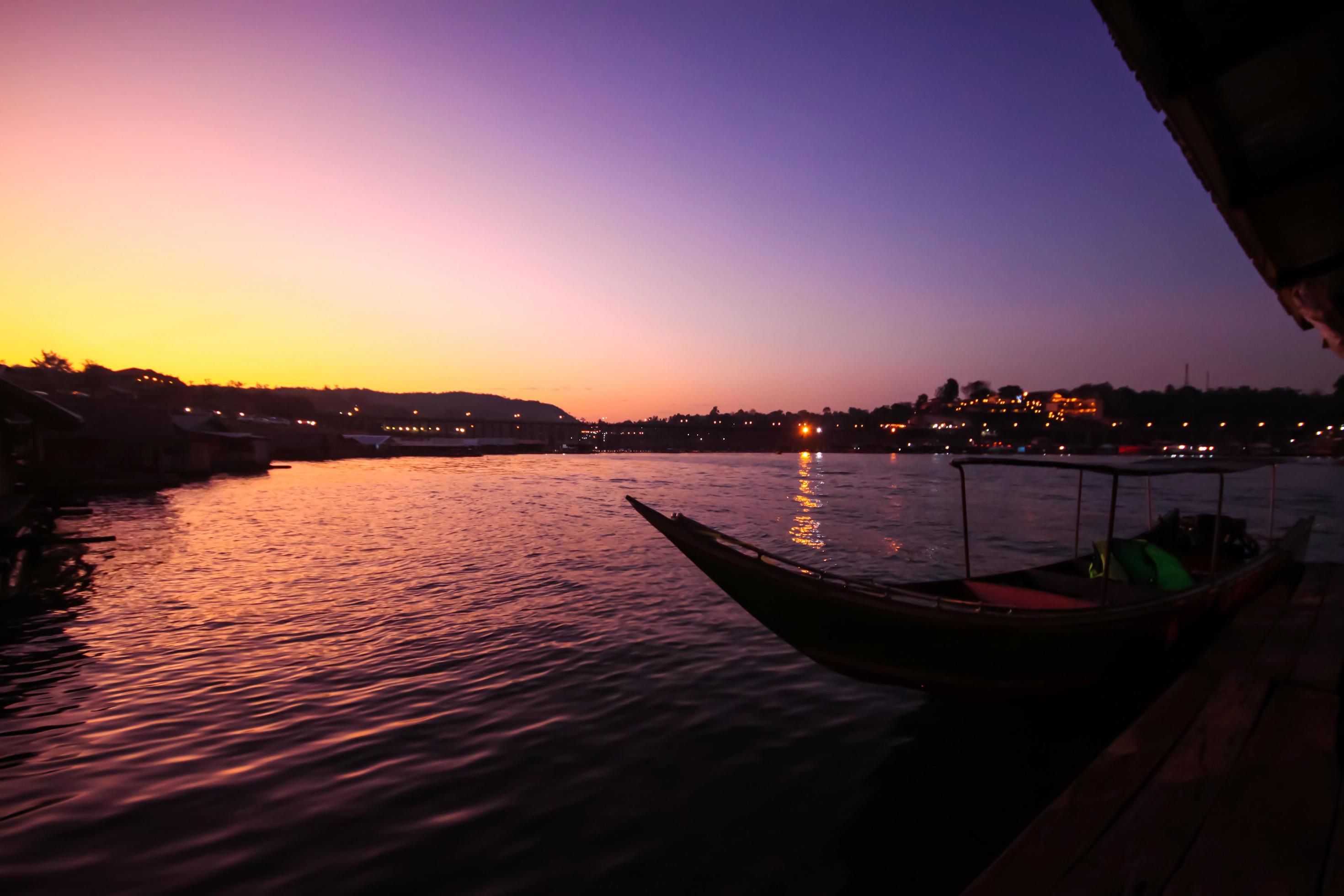 Beautiful Sunset and Silhouette of Thai tradition long-tail boat in the river near mon wooden bridge at Sangkhlaburi, Thailand Stock Free