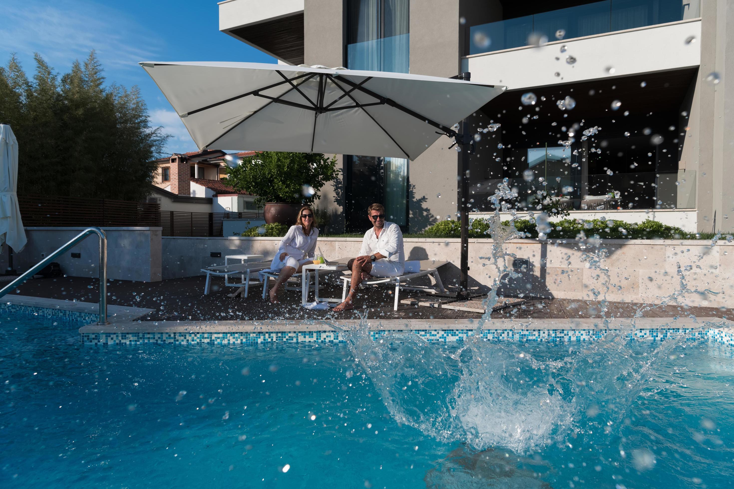 Happy family enjoys vacation in a luxury house with pool. Senior couple spends time with their son during the vacation. Selective focus Stock Free