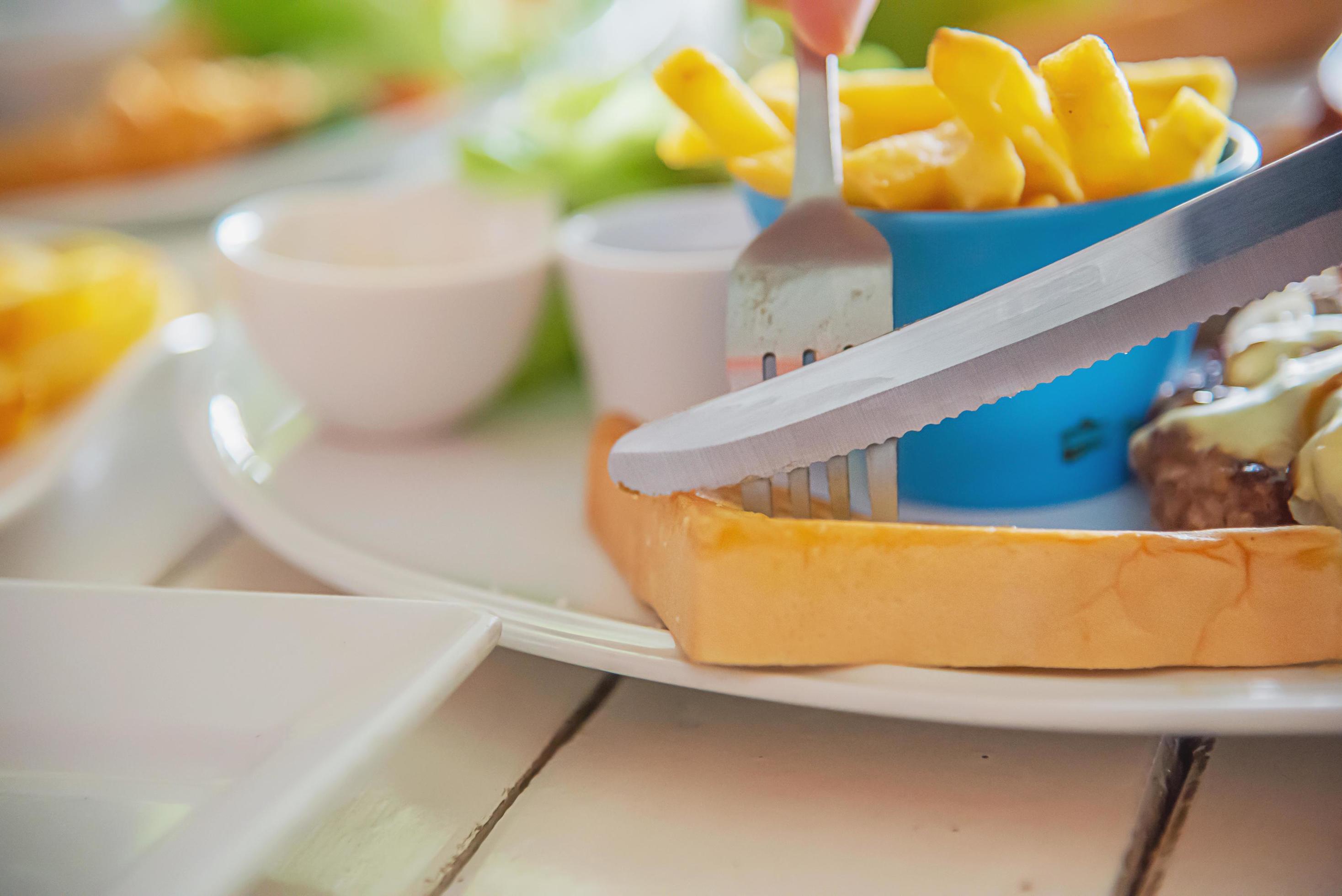 Closeup of people eat steak with sausage french fries and salad dish – people with fast food concept Stock Free