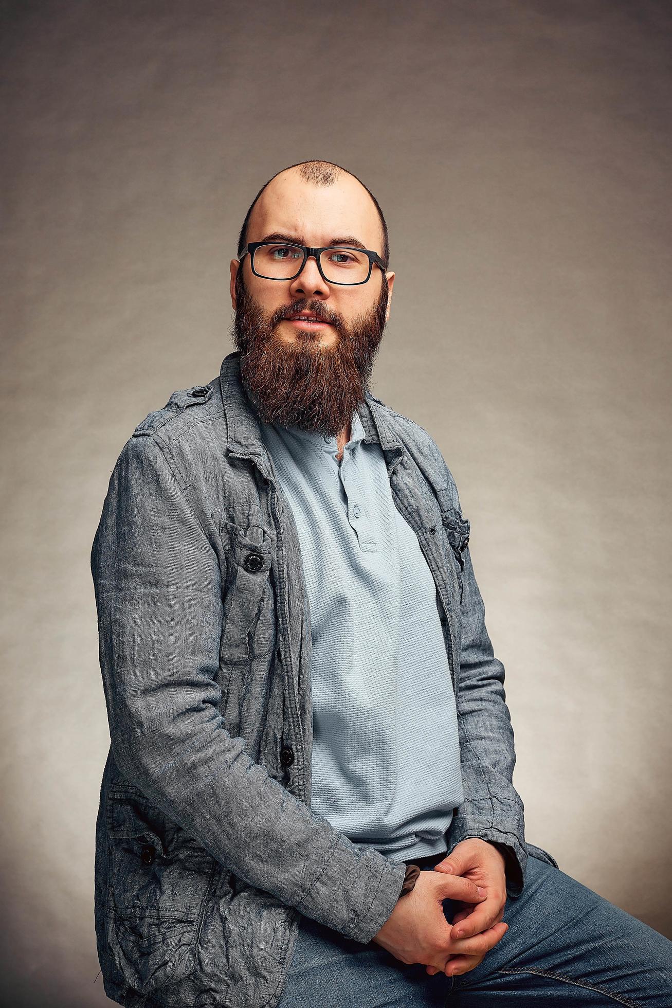 lifestyle successful young man with glasses , beard, fashionable denim jacket looking forward,male portrait in the Studio on a uniform background. Stock Free