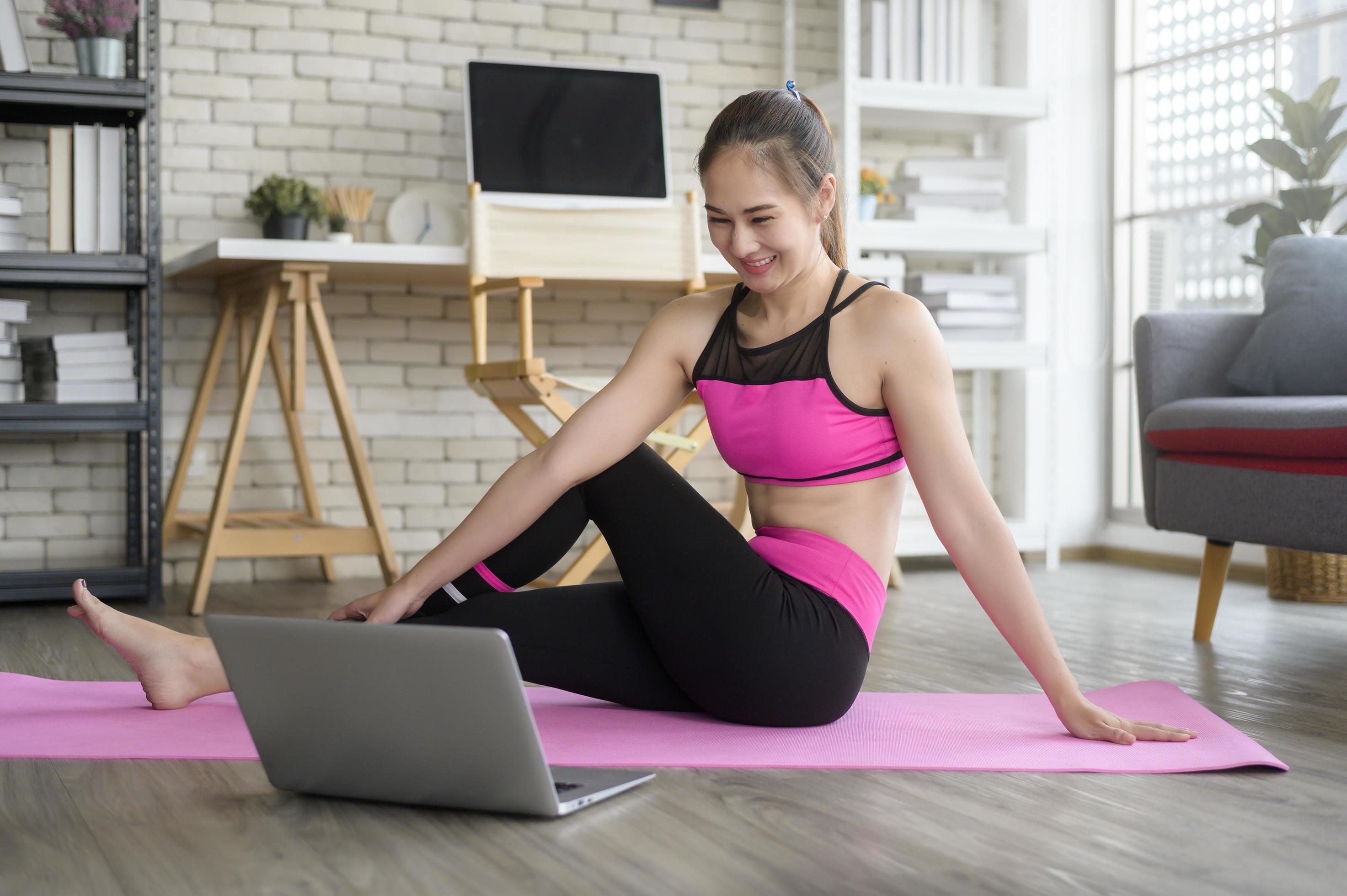 Fit young woman practicing yoga at home via online class with professional instructor, sport and healthy lifestyle concept. Stock Free