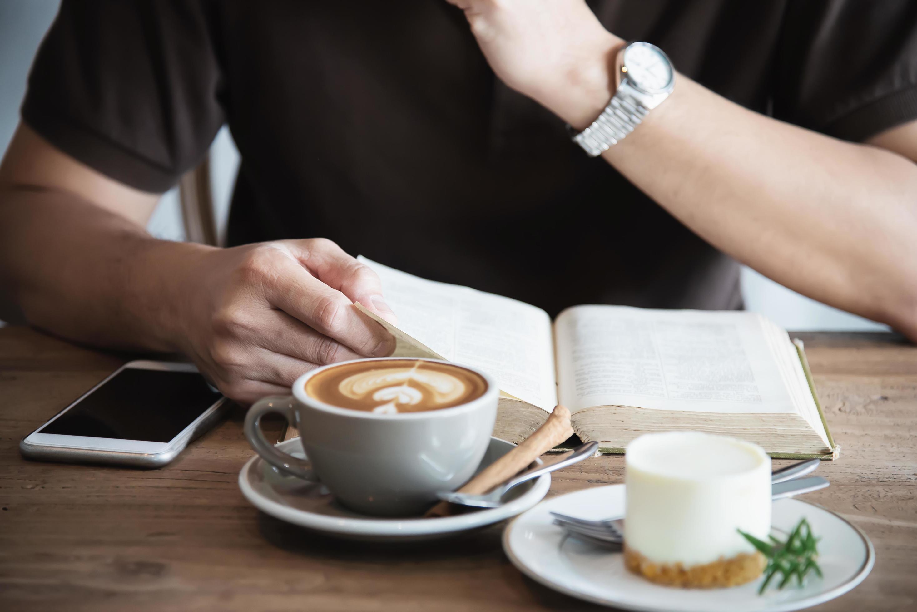 Relax Asian man drink coffee and read book in a modern style coffee shop – people with coffee cup easy lifestyle concept Stock Free