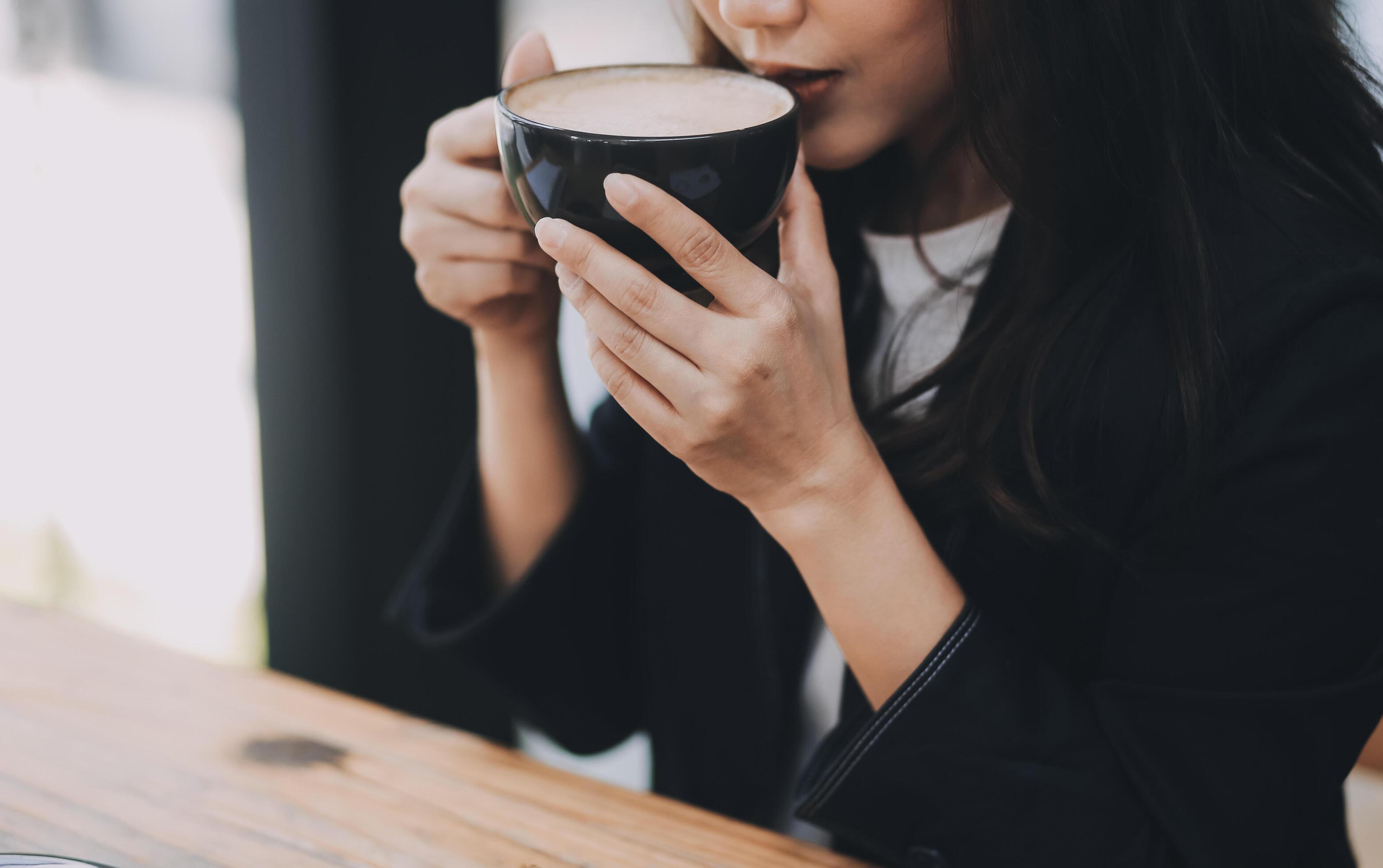 Beautiful young Asian businesswoman smiling holding a coffee mug and laptop working at the office. Stock Free