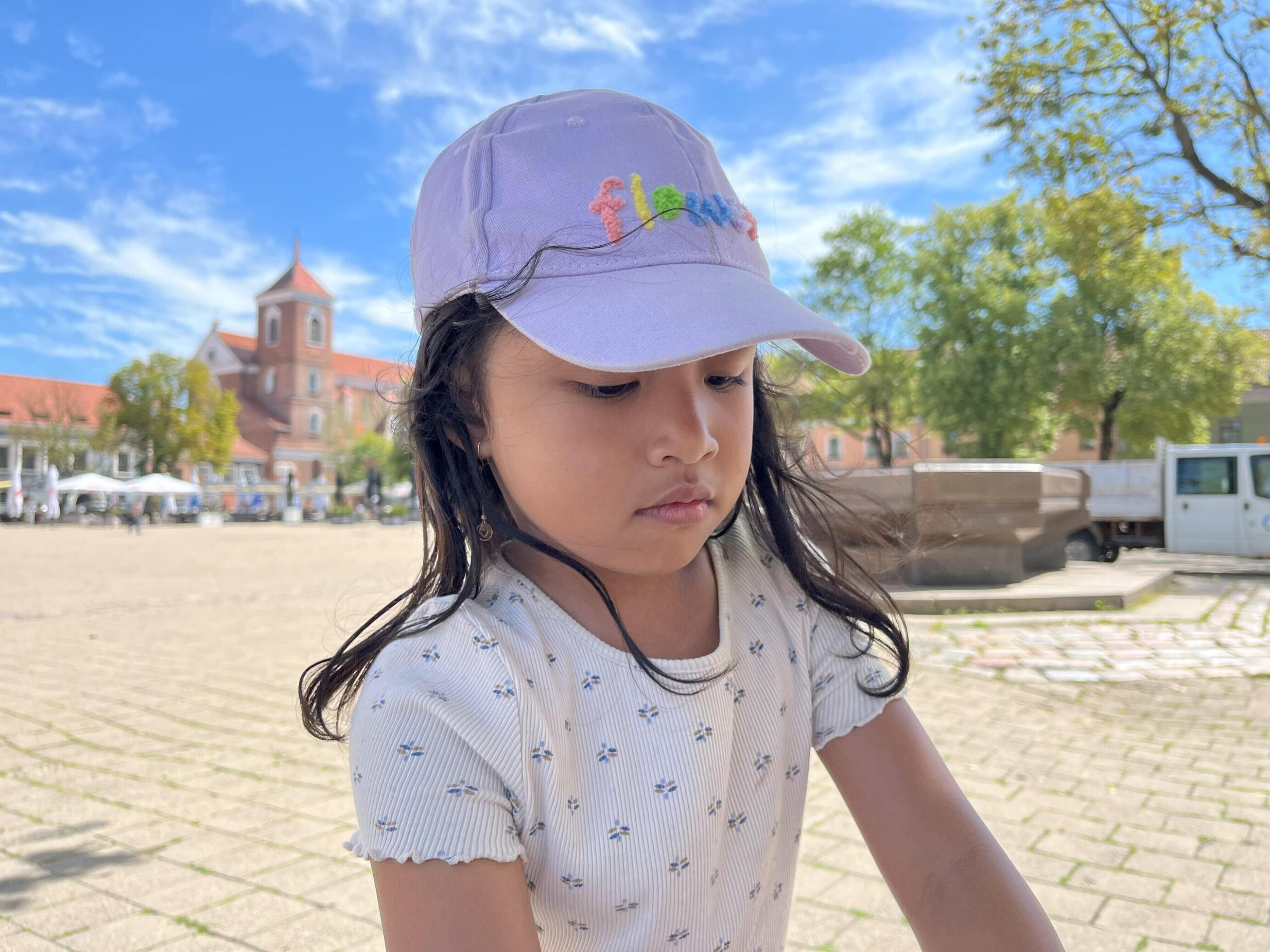 An Asian girl wearing a purple hat outdoors in summer. Adorable 5 year old child Stock Free