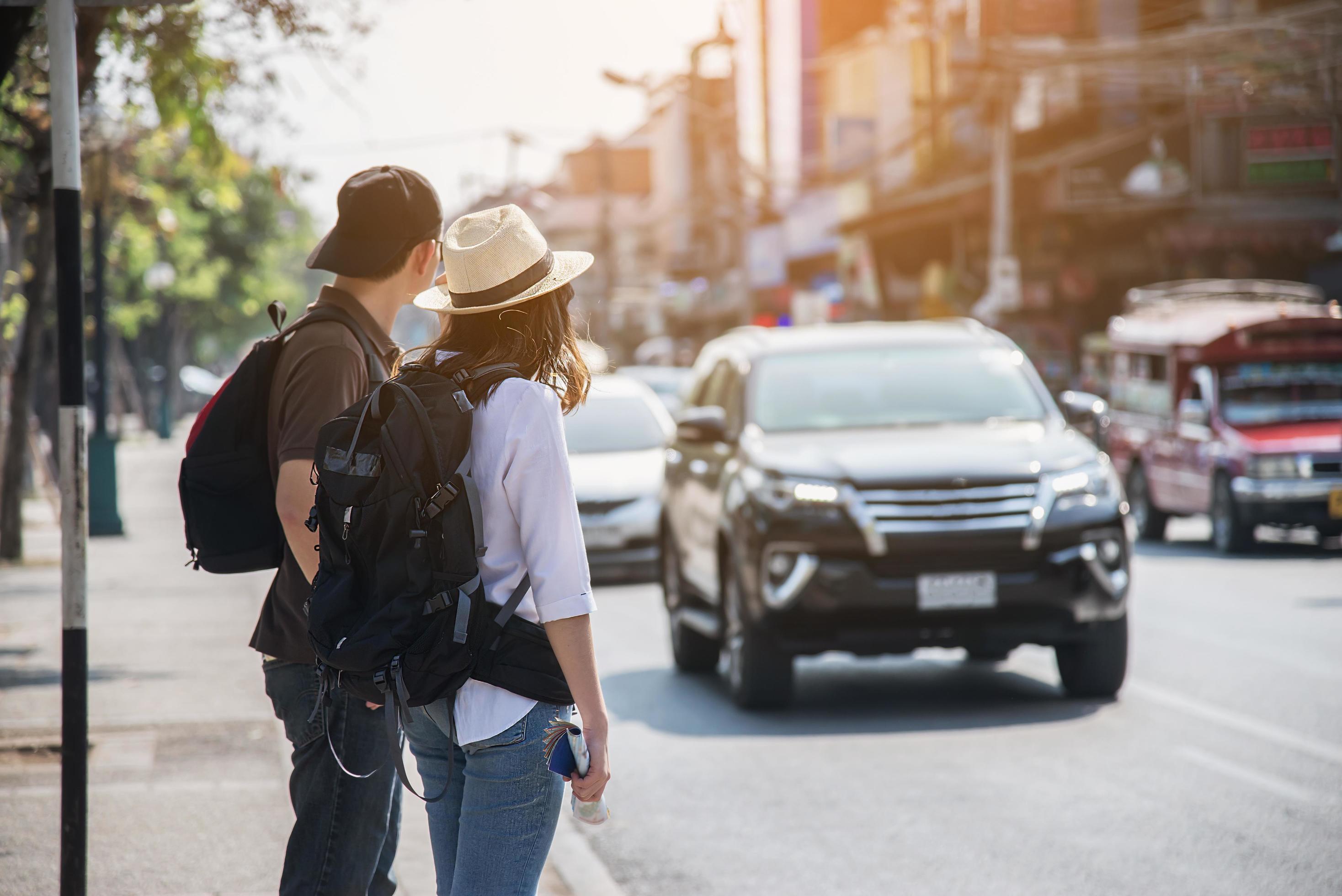 Asian backpack couple tourist holding city map crossing the road – travel people vacation lifestyle concept Stock Free