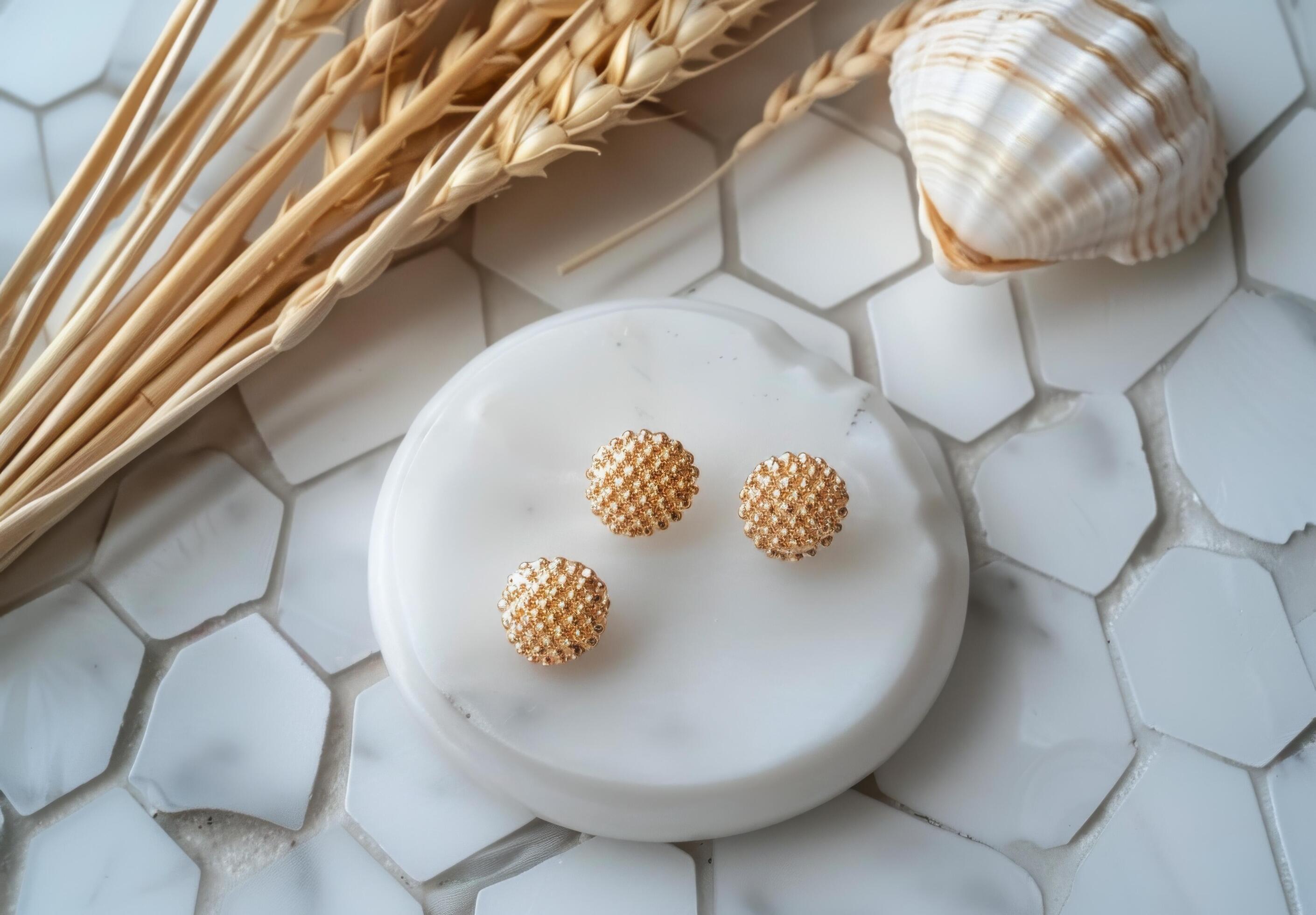 Gold Round Diamond Stud Earrings on White Marble Tray With Seashell and Wheat Stock Free