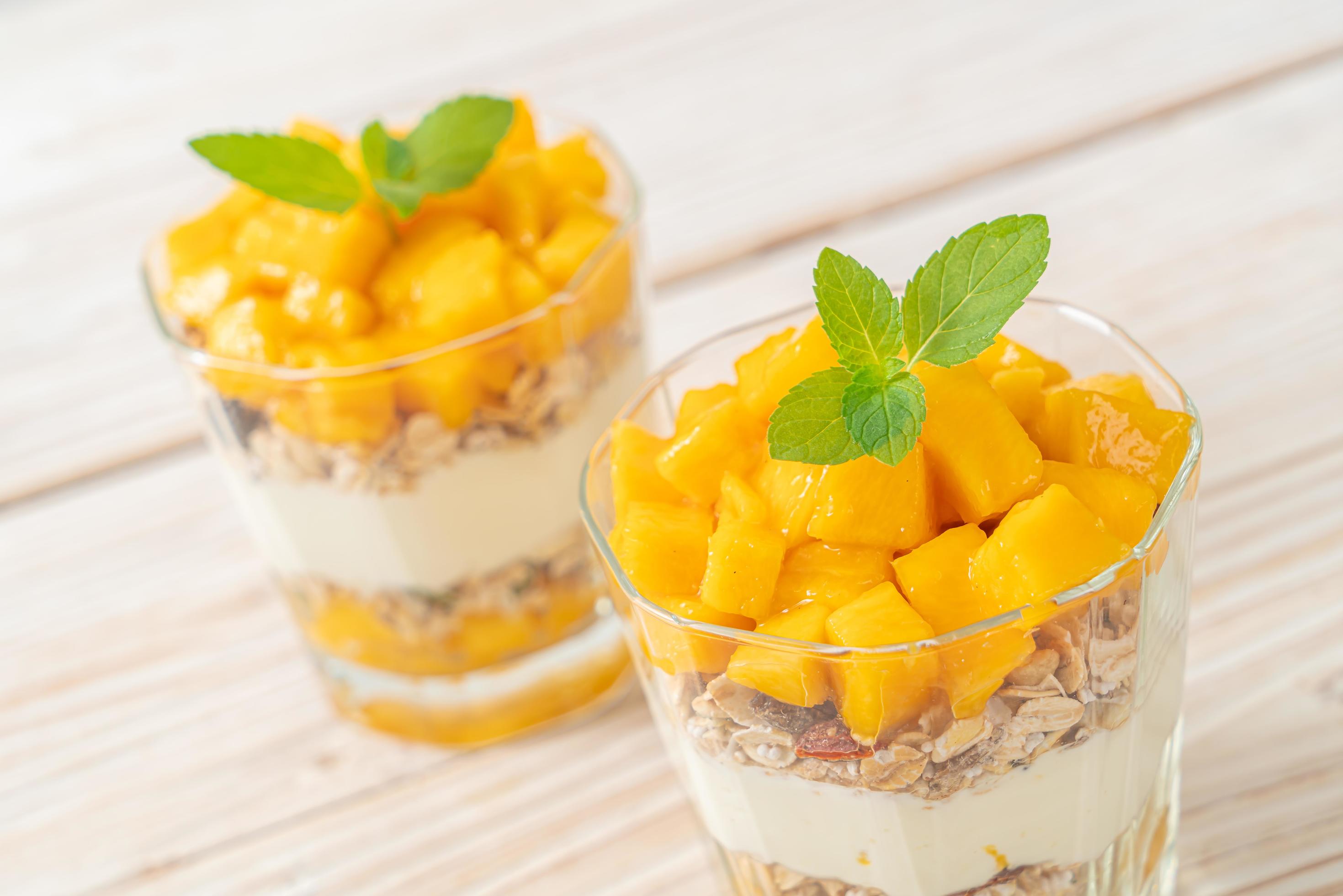 Fresh mango yogurt with granola in glass – healthy food style Stock Free