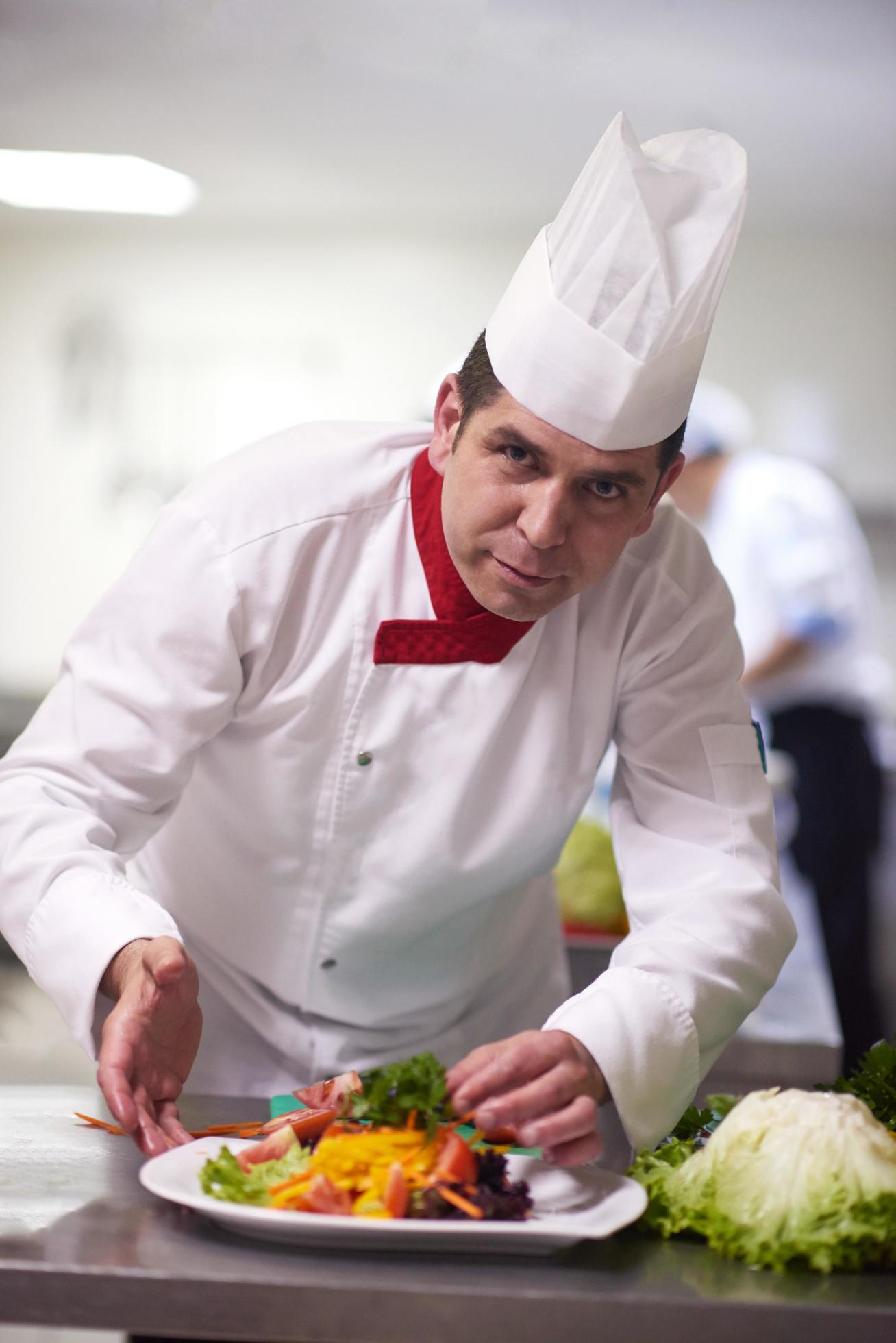 chef in hotel kitchen preparing and decorating food Stock Free