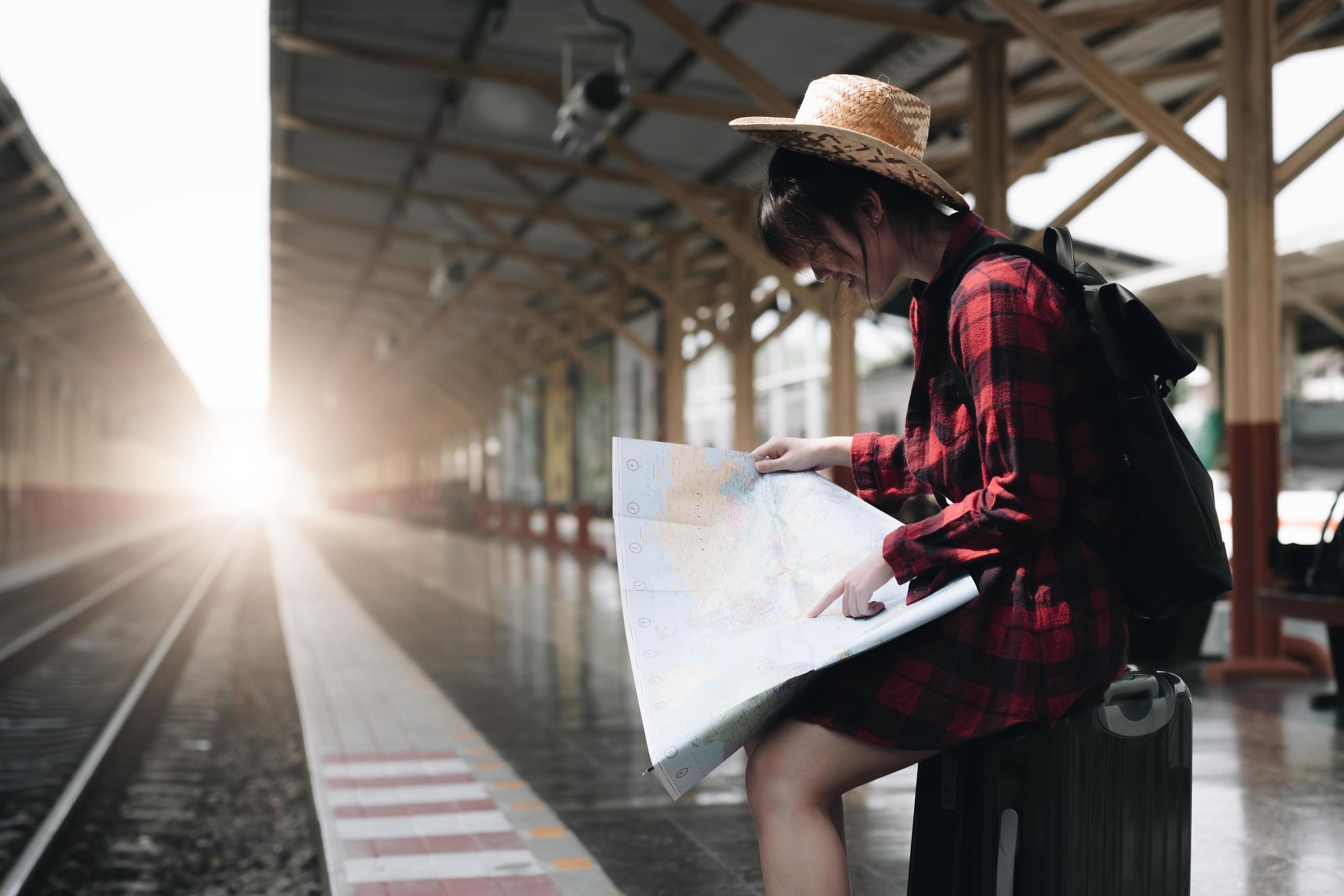 Young traveler woman looking on maps planning trip at train station. Summer and travel lifestyle concept Stock Free