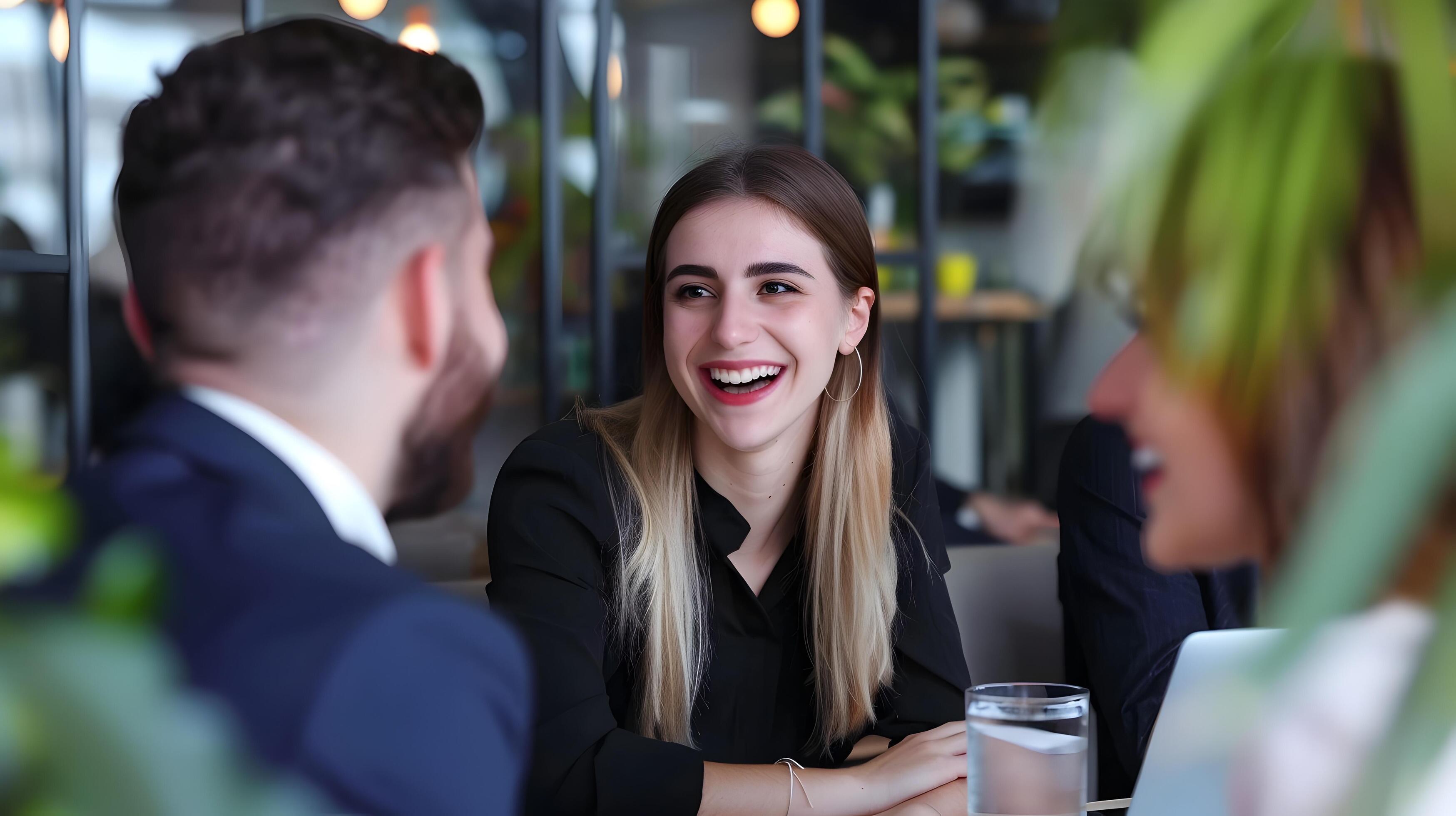 Smiling Young Professional Woman in Casual Outfit Collaborating with Coworkers at Office Desk Stock Free