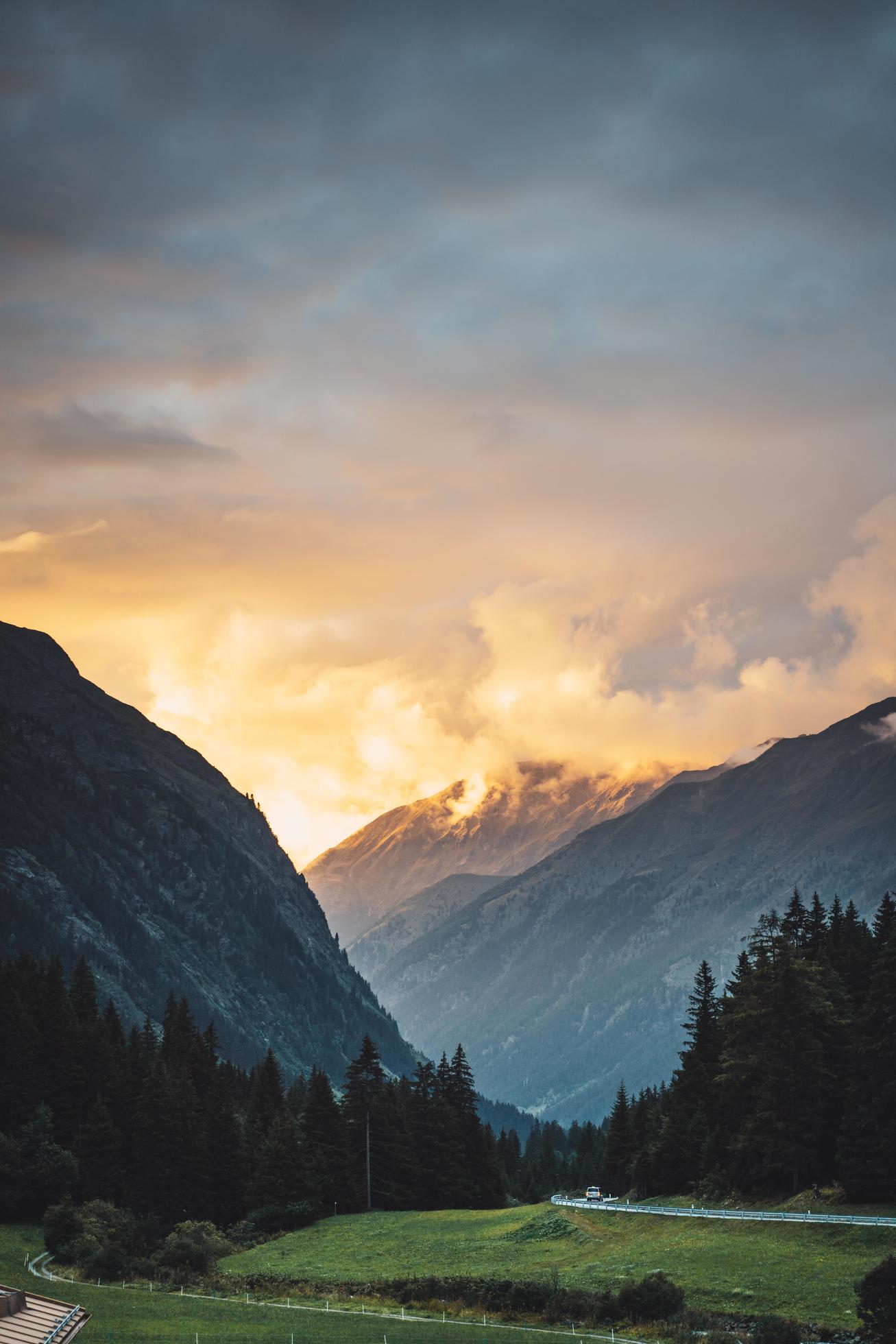 Sunset through clouds near mountains Stock Free