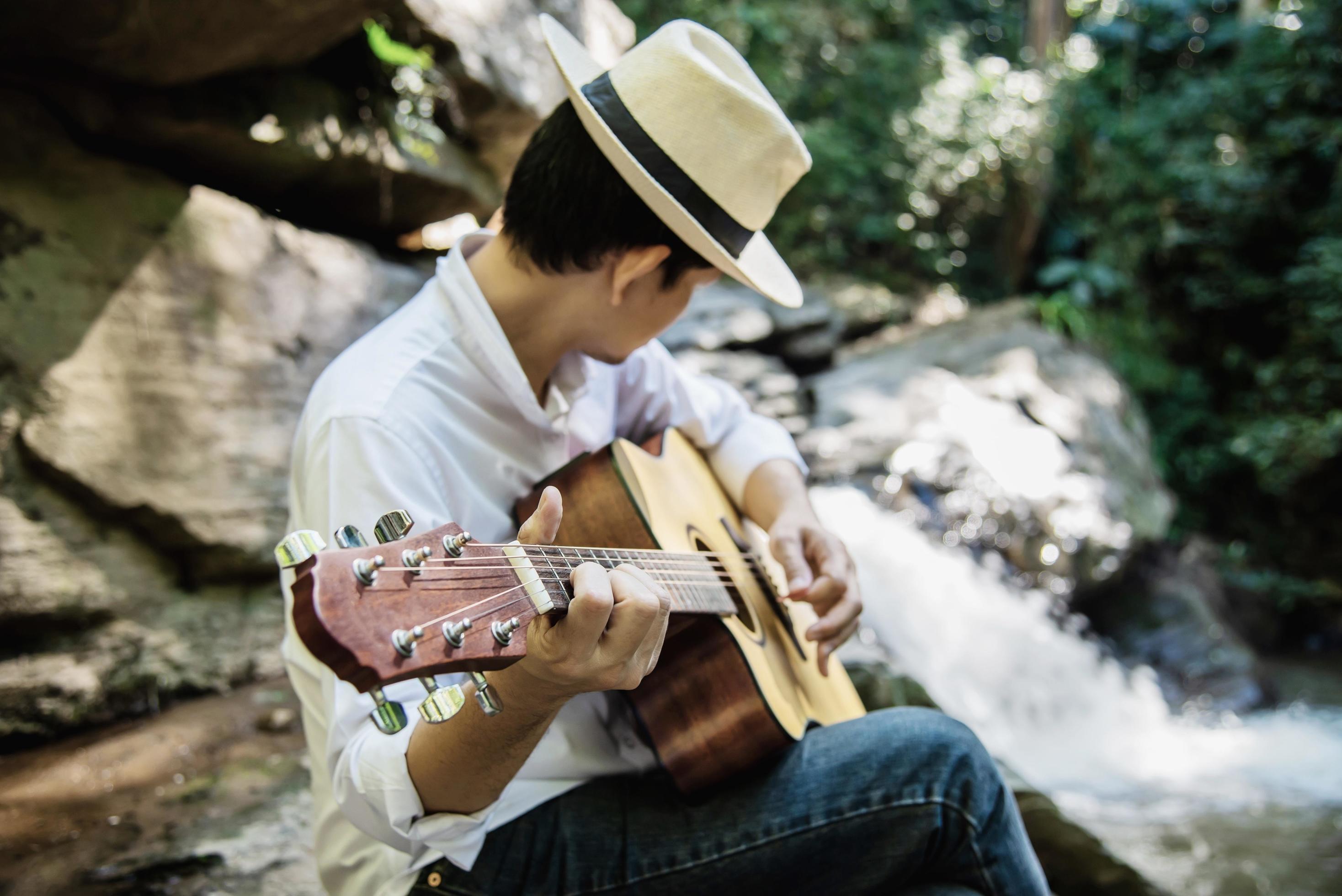 Man play ukulele new to the waterfall – people and music instrument life style in nature concept Stock Free