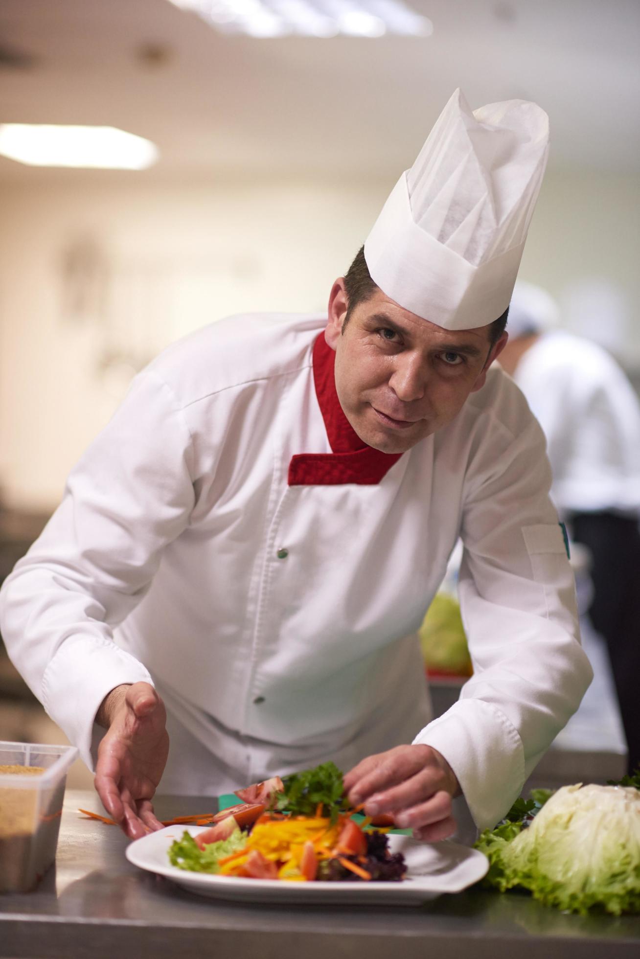 chef in hotel kitchen preparing and decorating food Stock Free