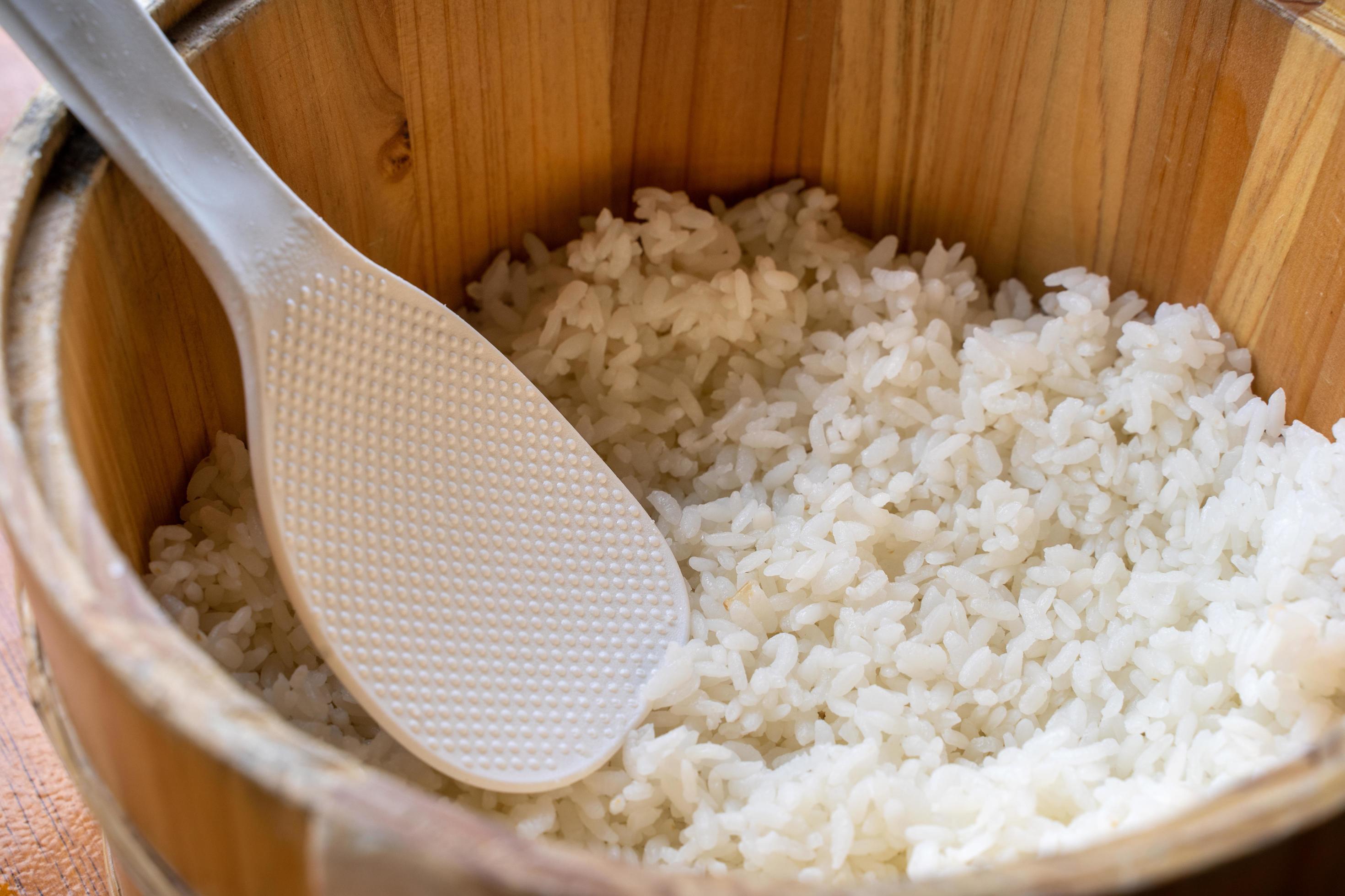 Delicious cooked plain rice in a big wooden bowl ready-to-eat with white rice spatula spoon at restaurant table, close up, lifestyle. Stock Free