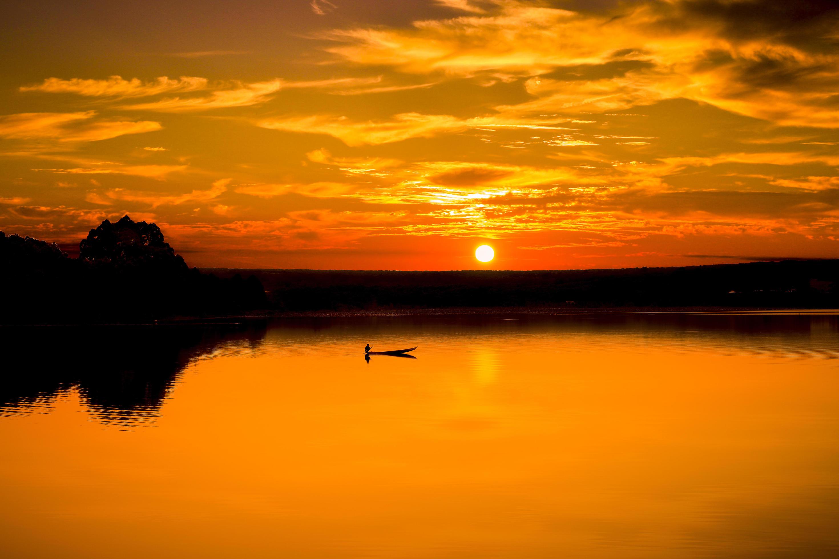 Man and boat on water at sunset Stock Free