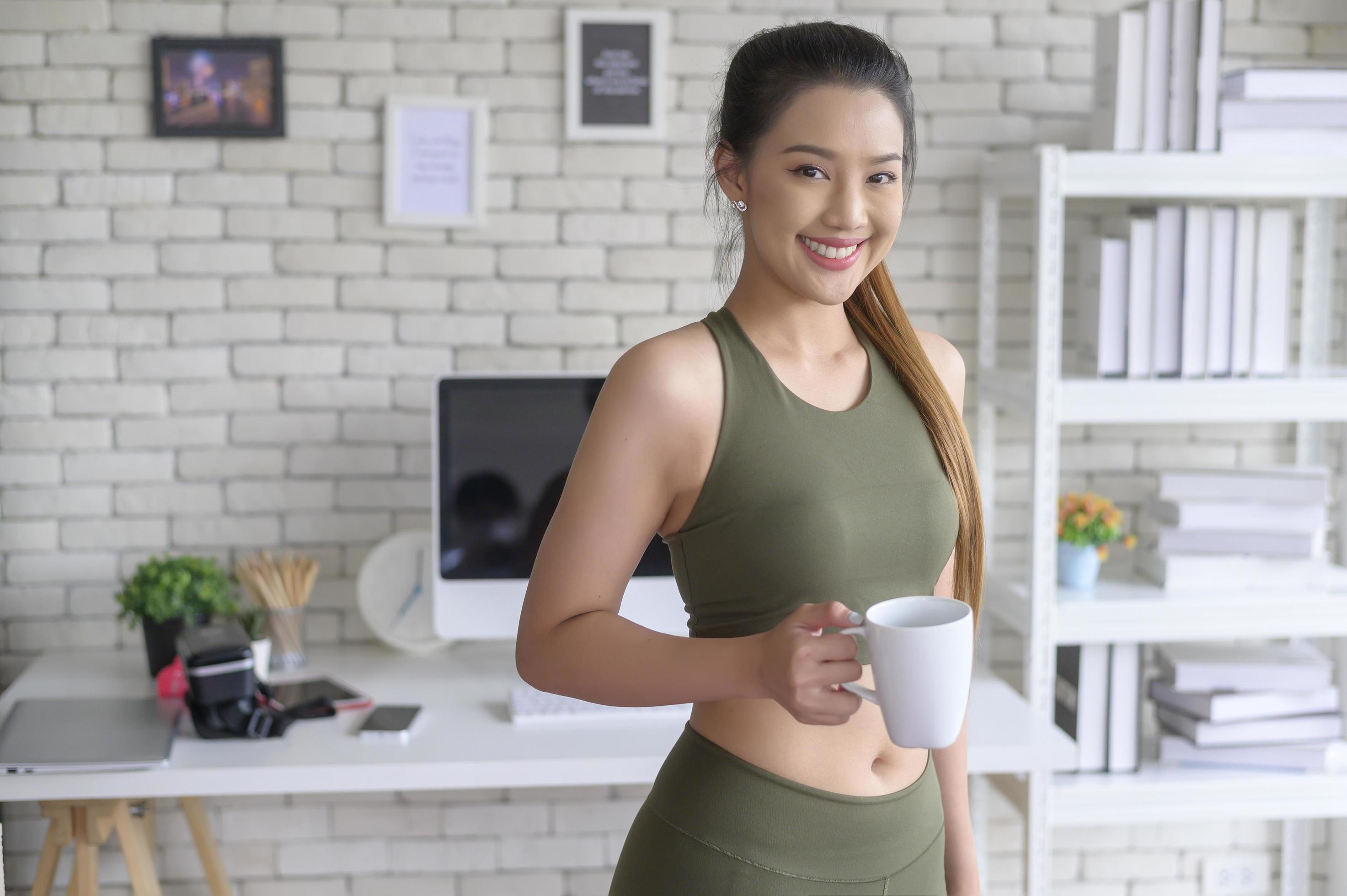 Young fitness woman in sportswear having a cup of coffee after exercising at home, Healthy and Lifestyles. Stock Free