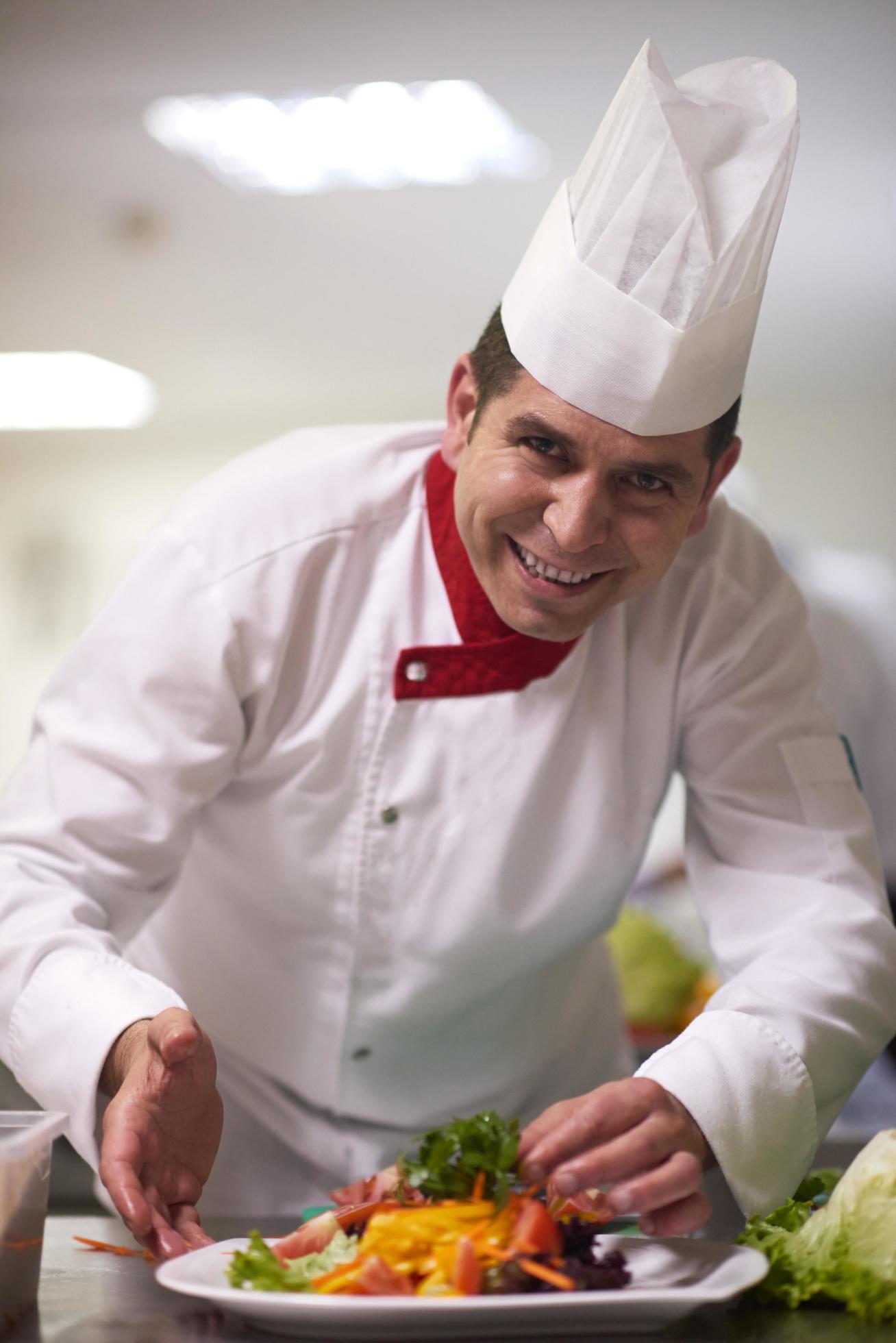 chef in hotel kitchen preparing and decorating food Stock Free